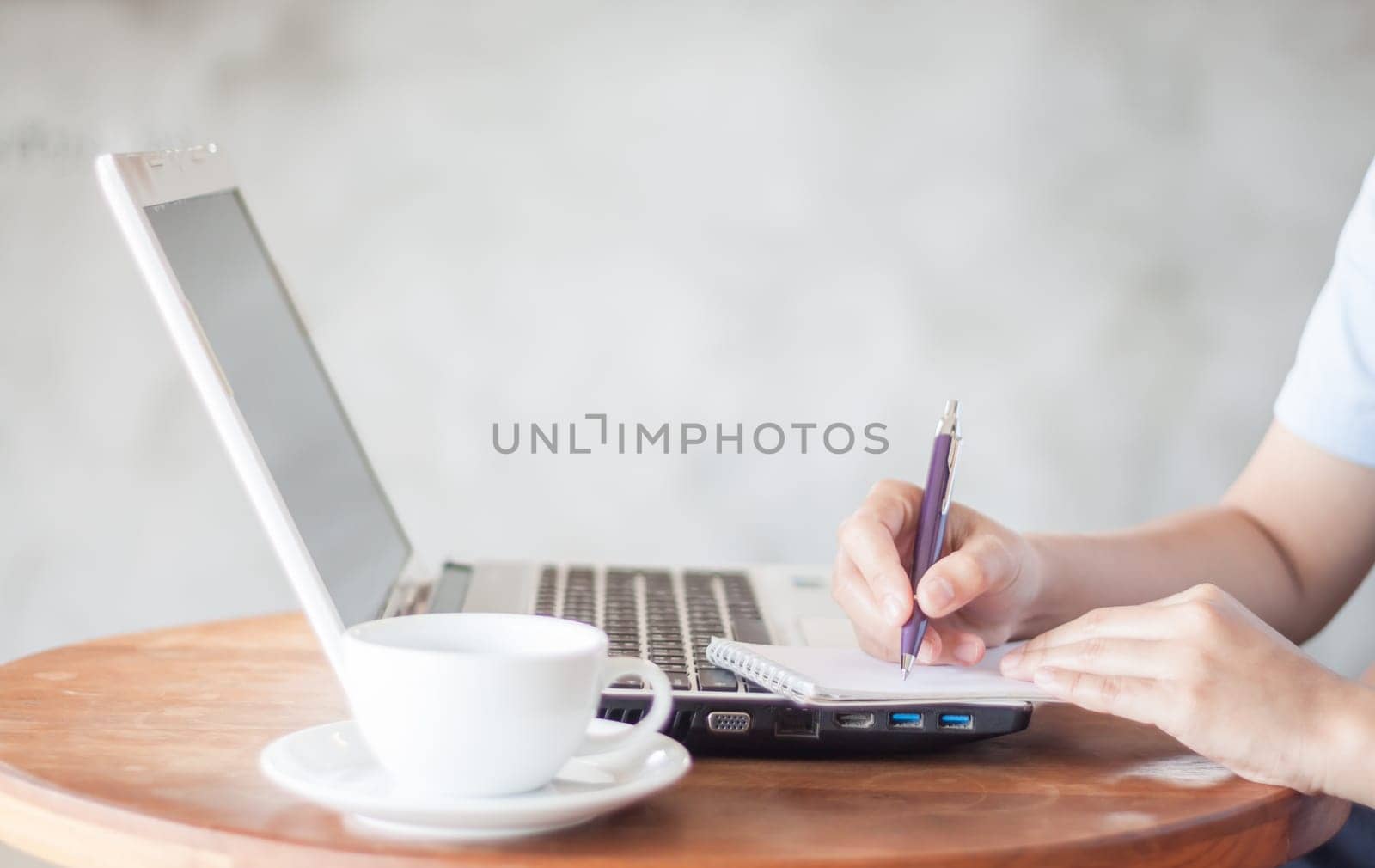 Woman writing on notepad in coffee shop, stock photo