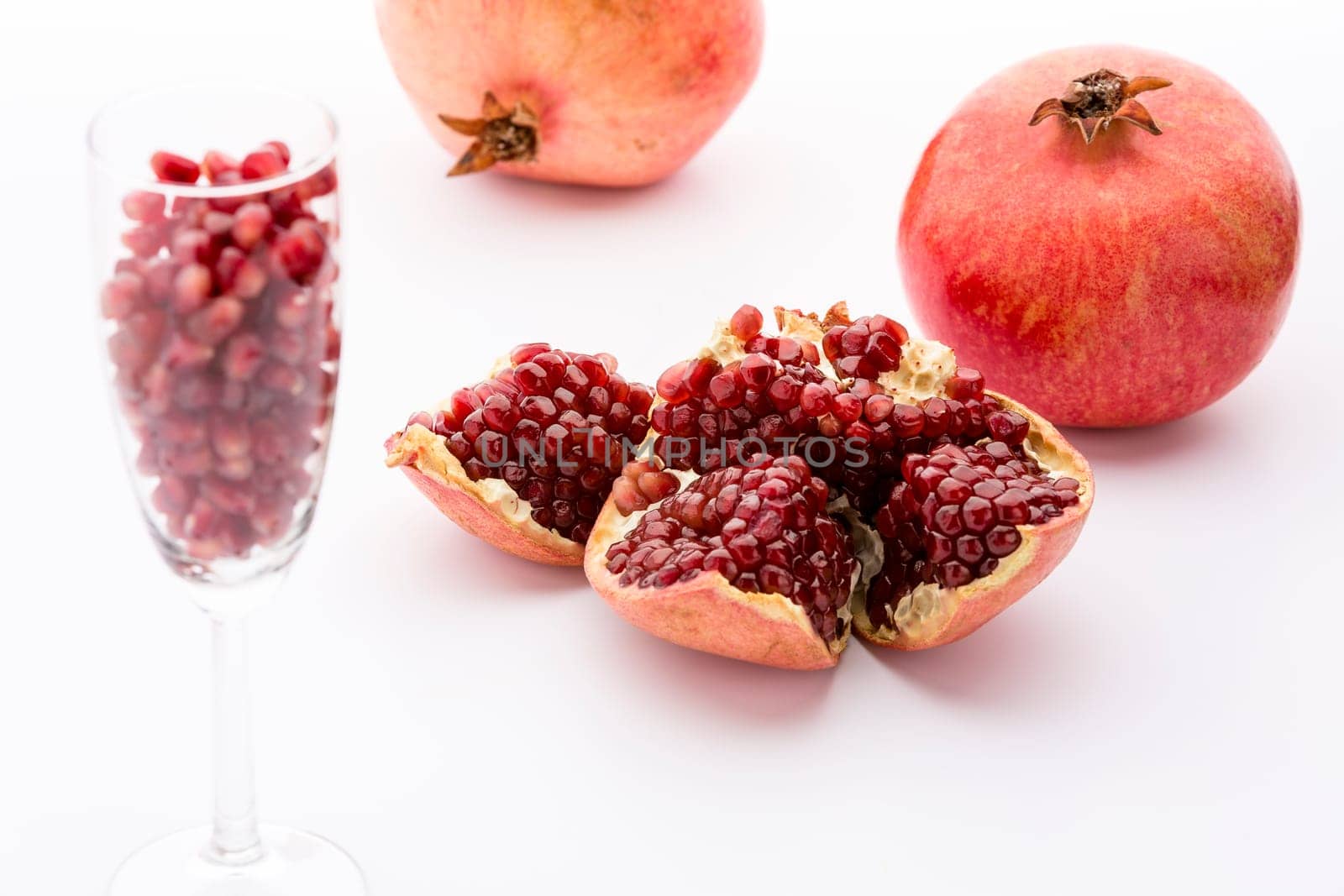 Broken paradise fruit with red,ripe cores in the core casing. Paradise fruit seeds in a champagne glass. Two whole fruits.