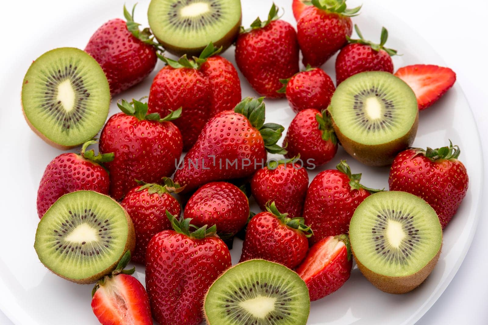 A plate full of strawberries and halved kiwis.