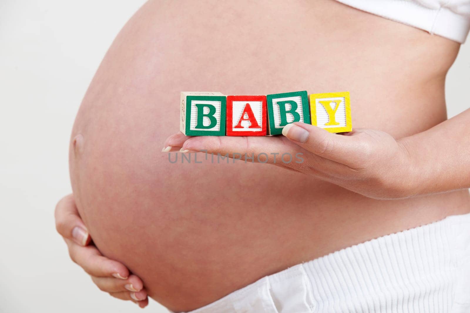 Pregnant Woman Holding Wooden Blocks Spelling Baby