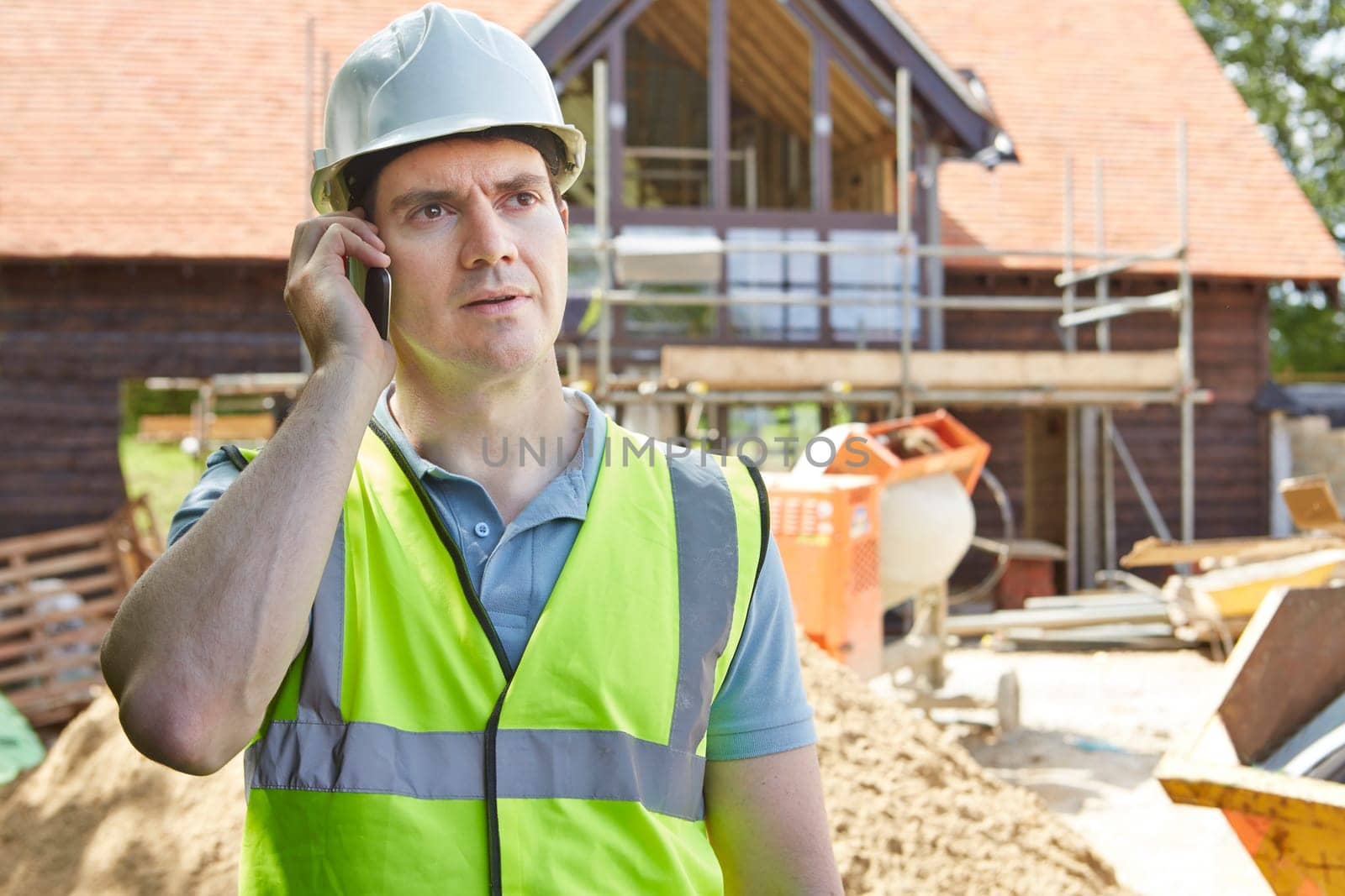 Construction Worker On Building Site Using Mobile Phone