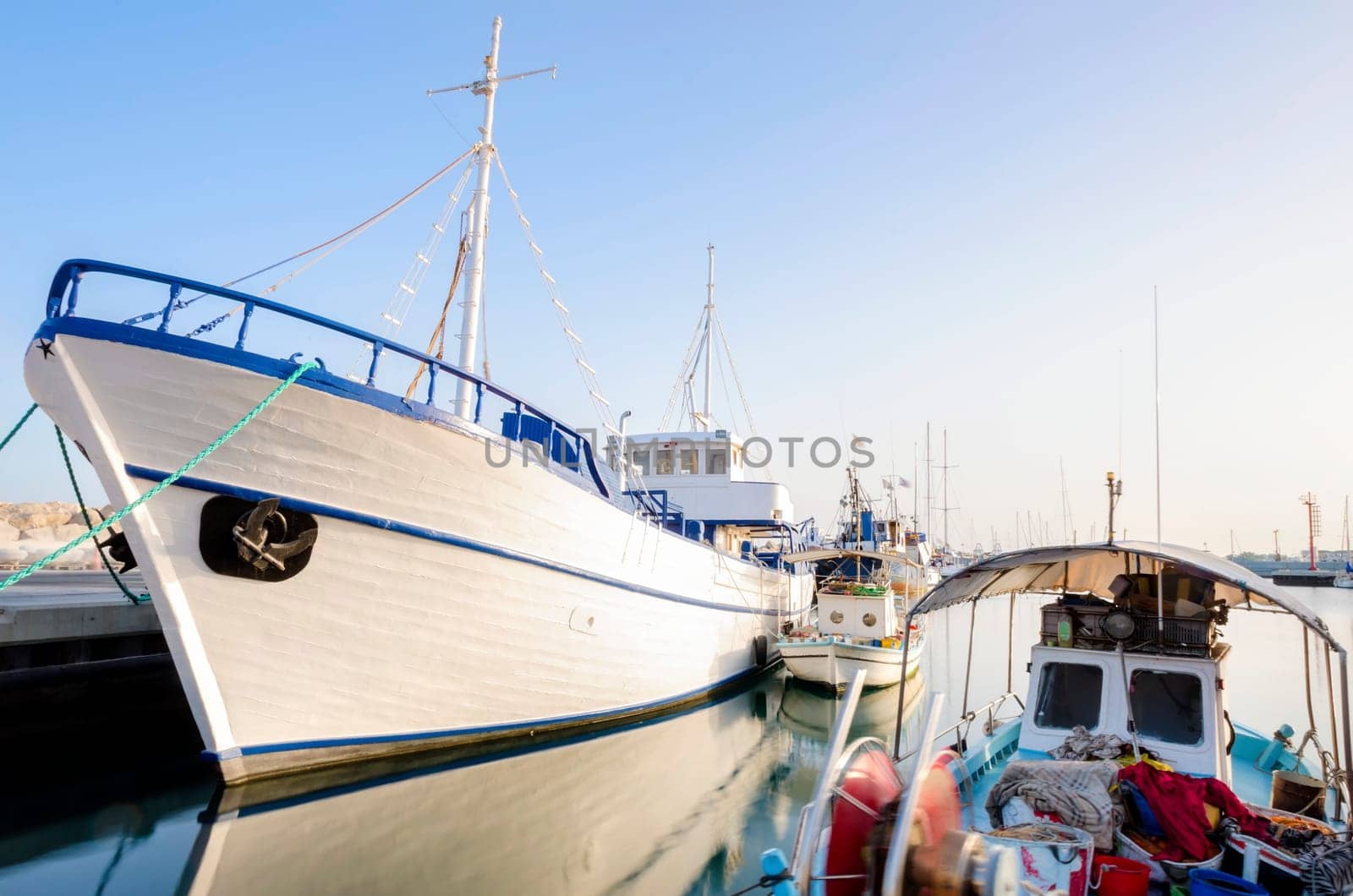 Fishing boats docked at the Limassol old port in Cyprus, next to the Marina part of the ports authority. A view of the harbor, the mediterranean sea, the water, boat and fish nets and fishing equipment.