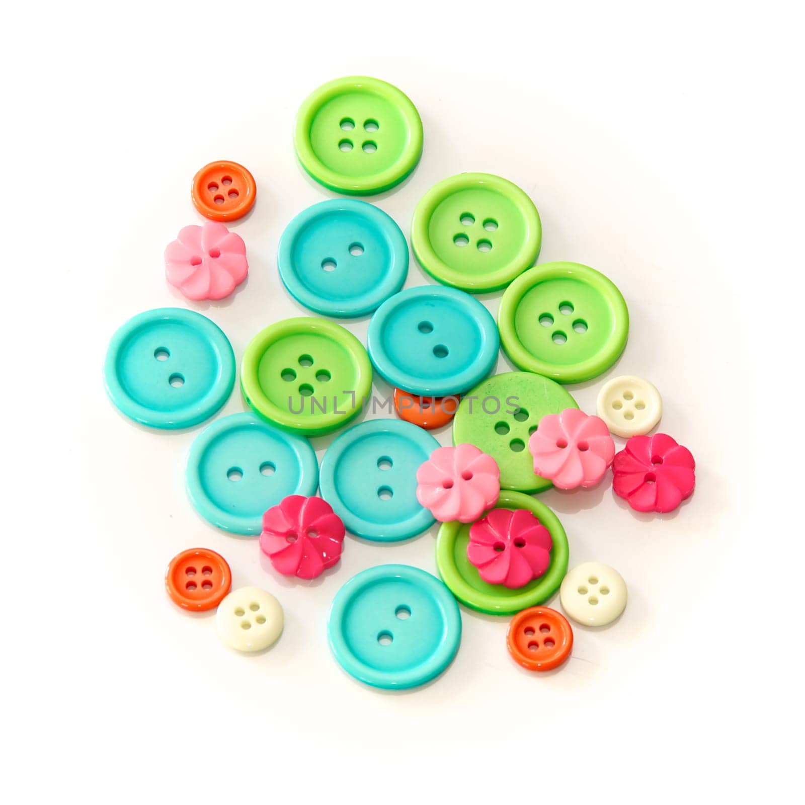 An assortment of shapes, sizes, and colors of buttons, round and flower shaped, shot over white.