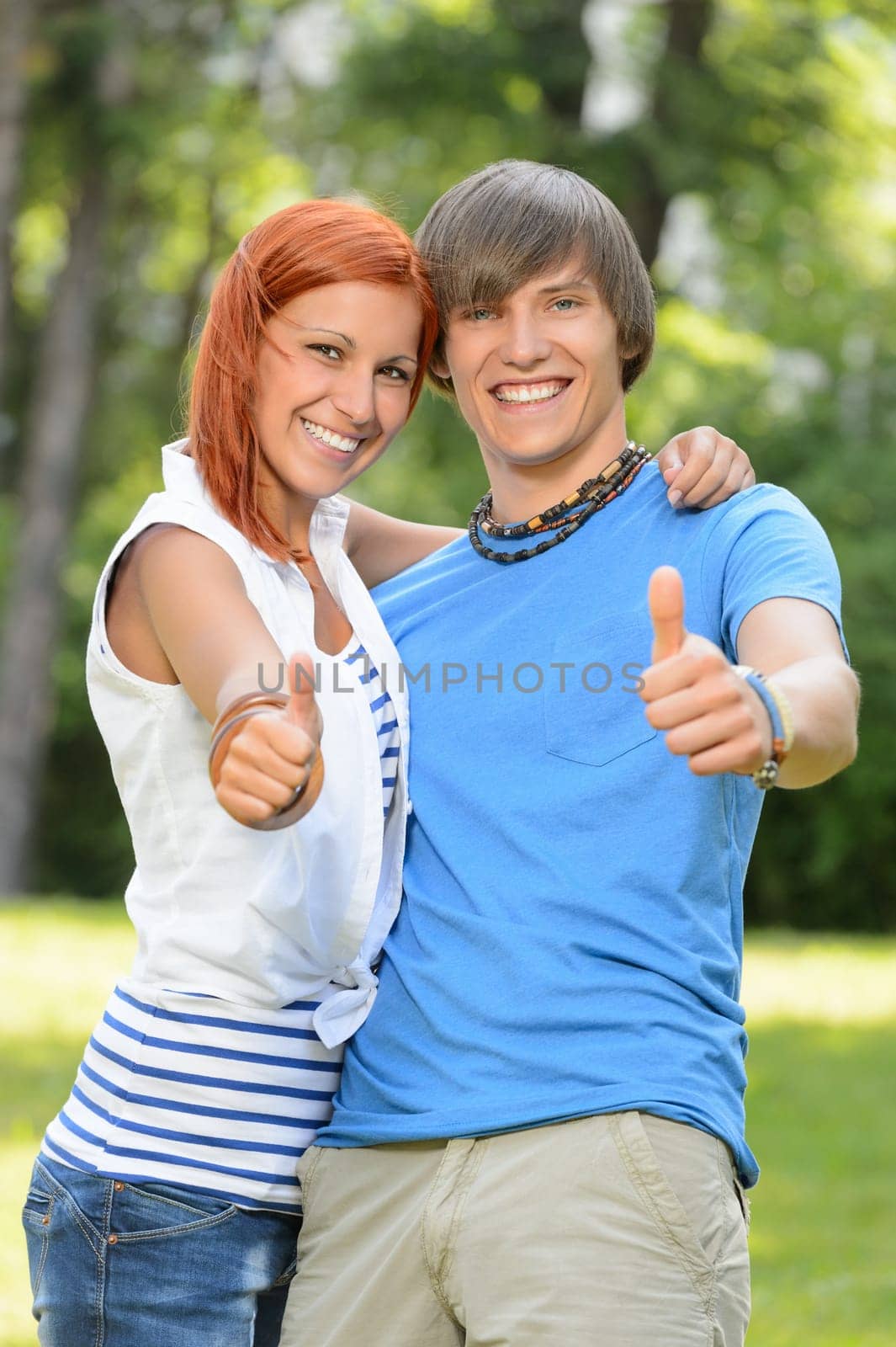 Teenage friends show thumb up in sunny park