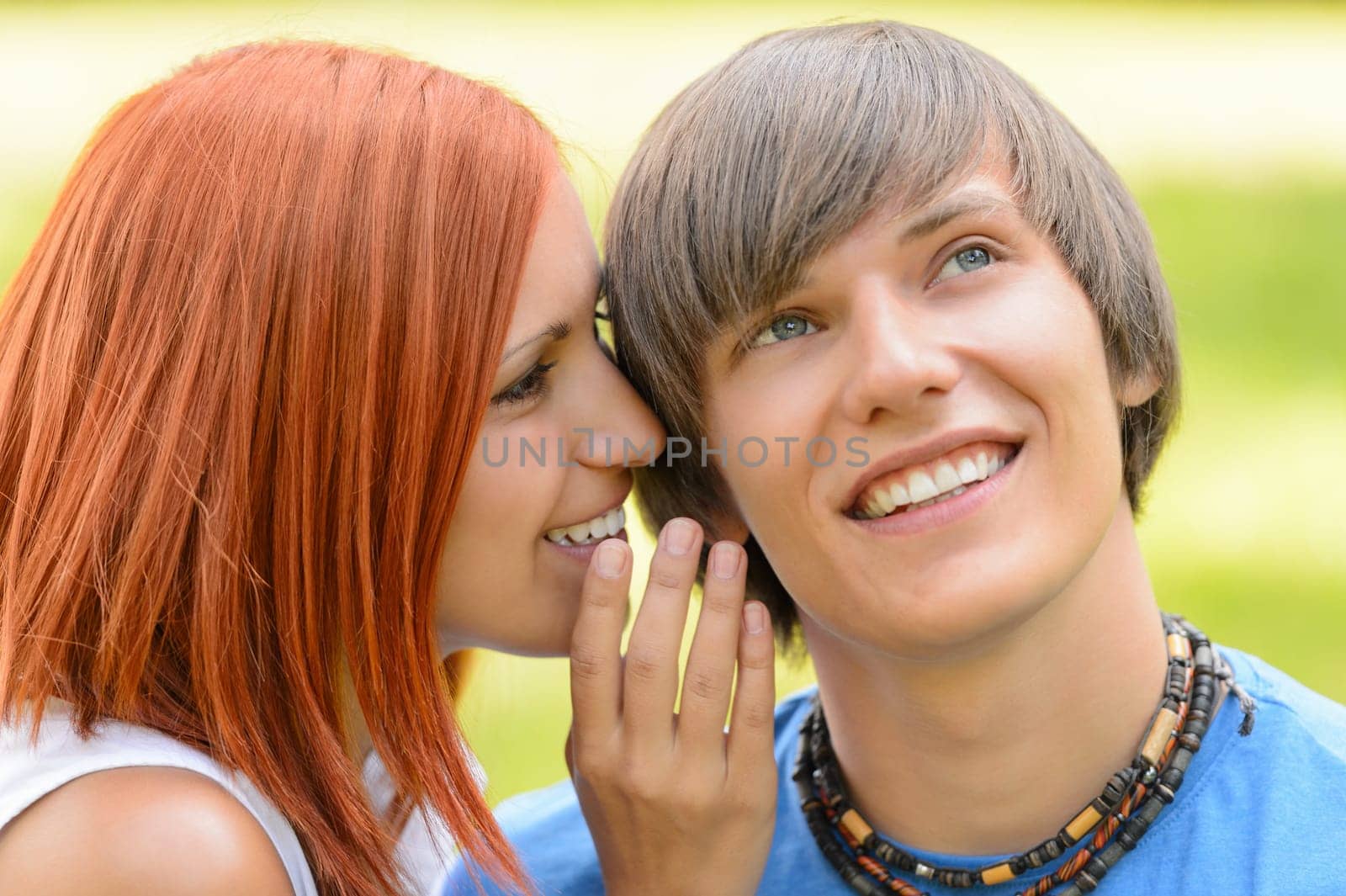 Teenage woman whispering to her boyfriend loving couple summer time