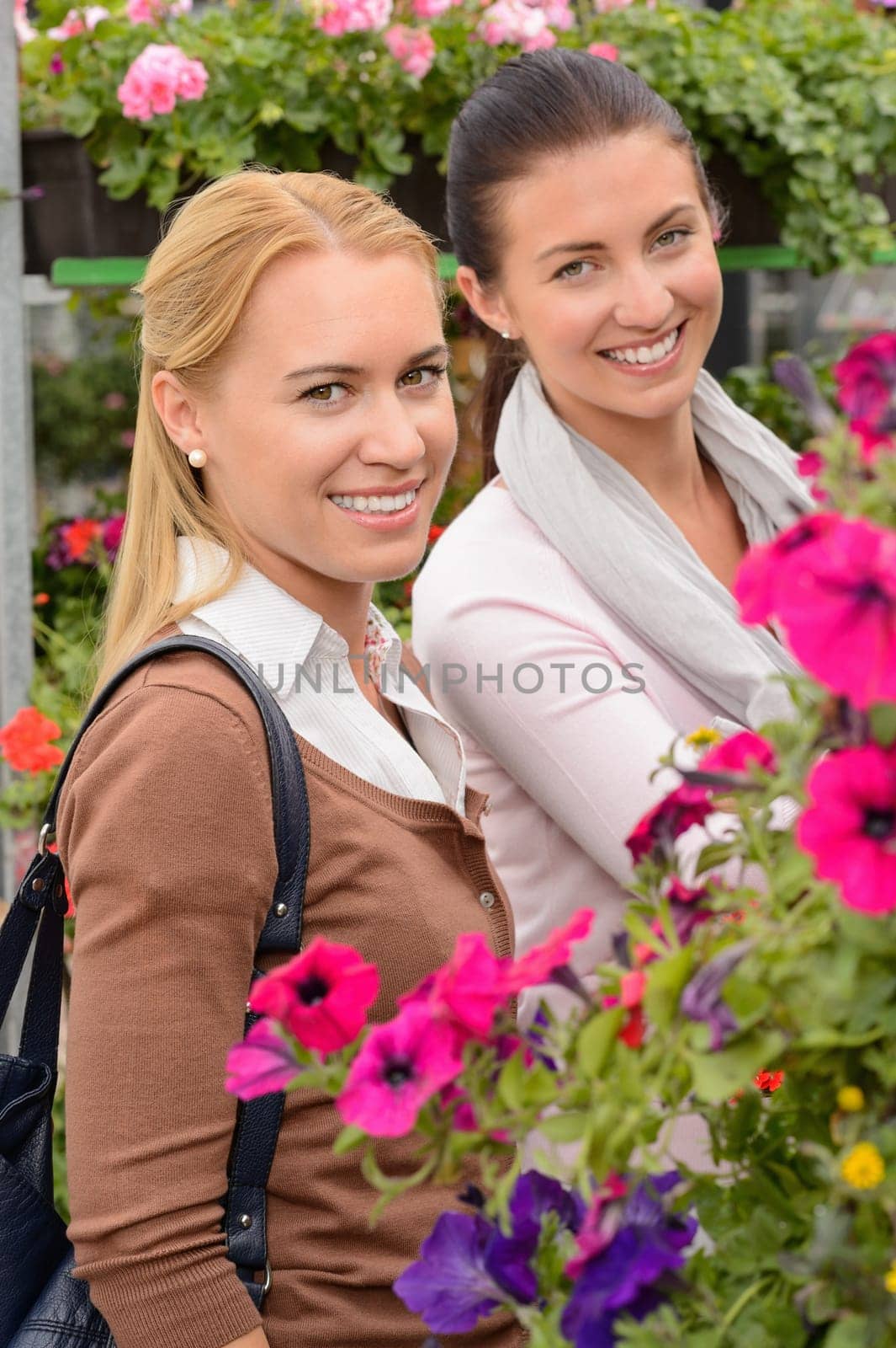 Smiling customer women in garden center shopping for colorful flowers