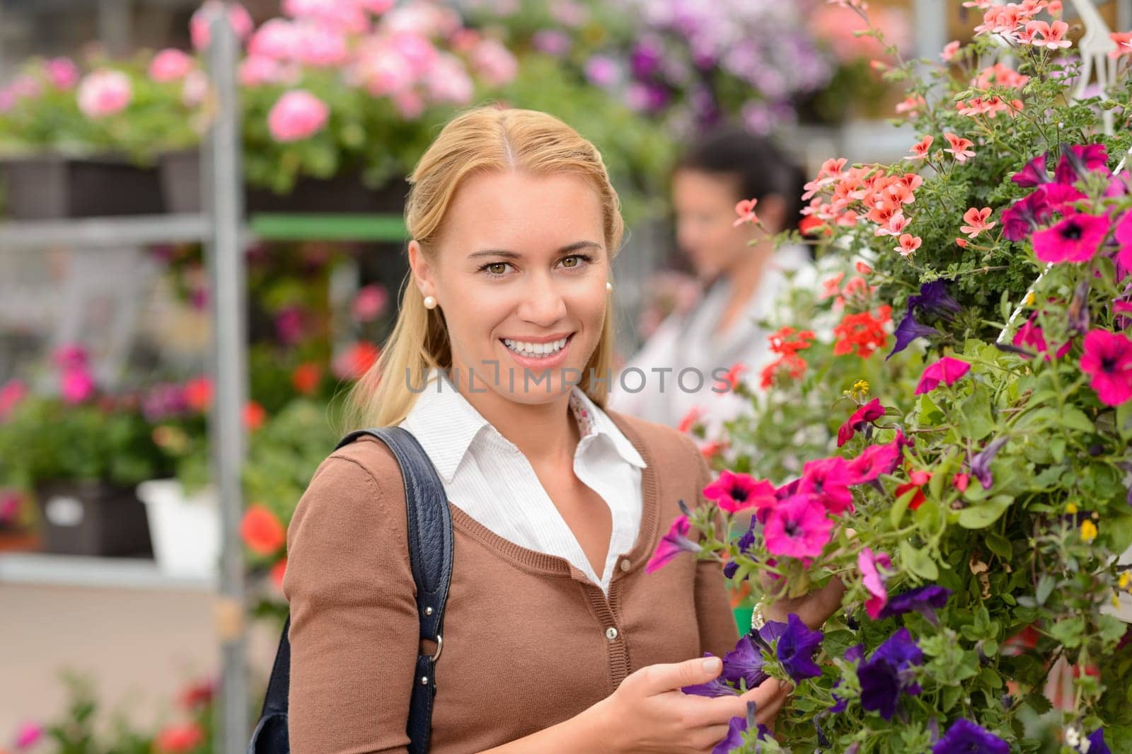 Smiling customer woman with colorful flowers in garden center