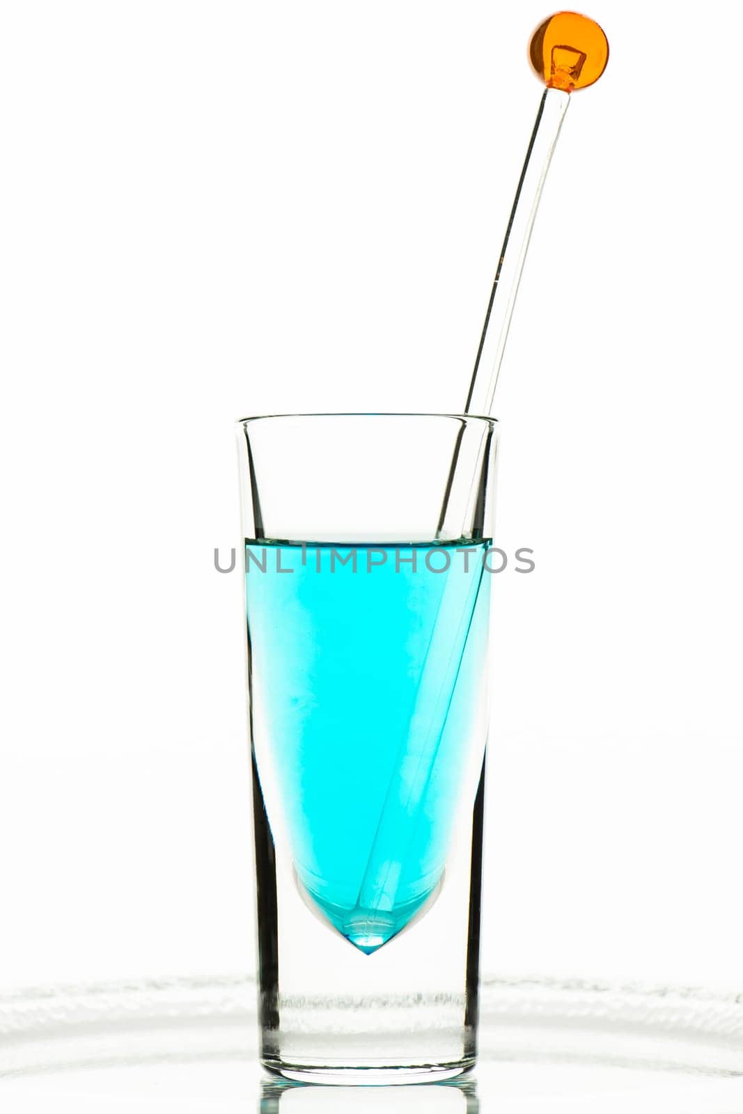 Turquoise liquid in a glass with a stirring rod