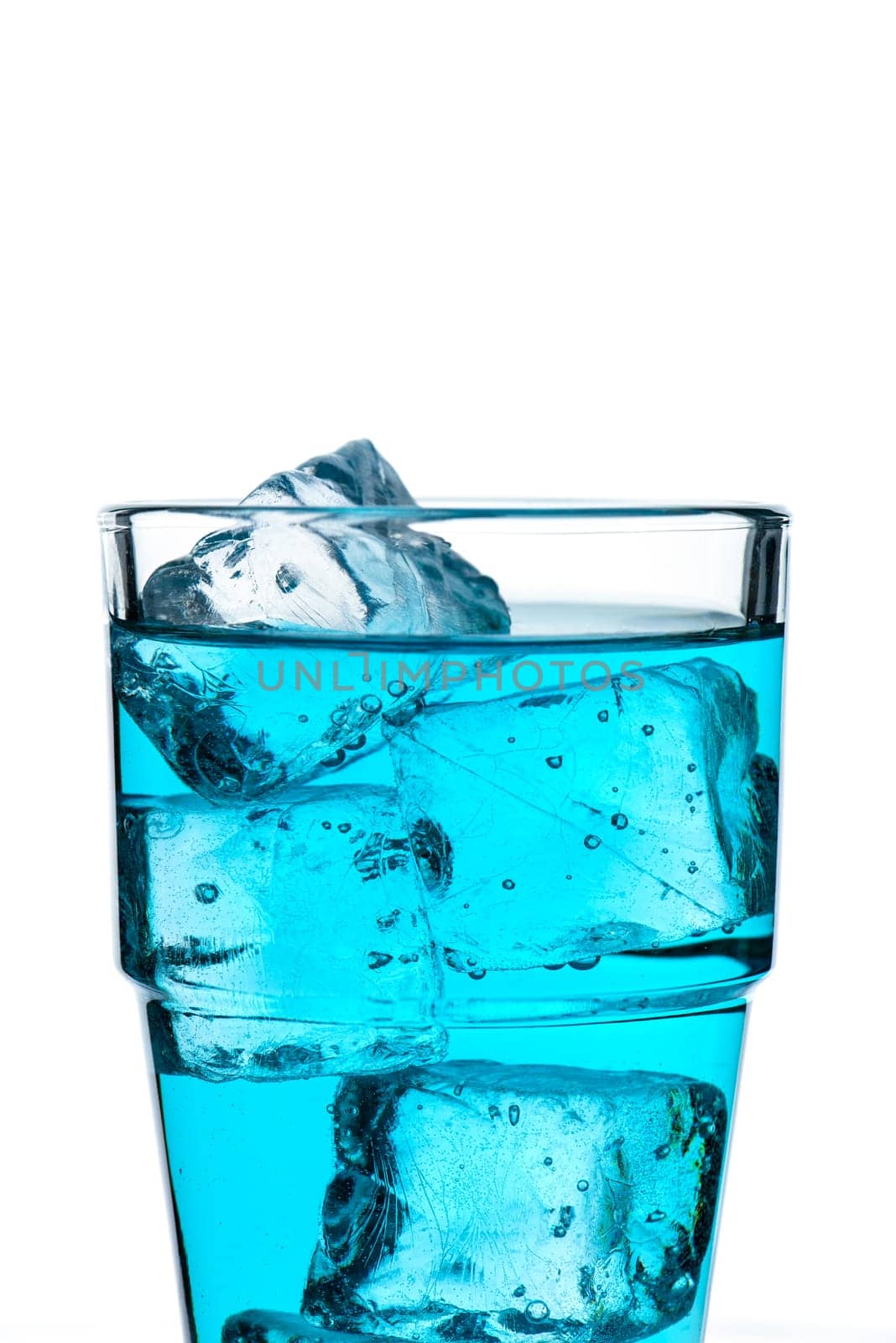 Glass with ice cube and drink in blue with text space