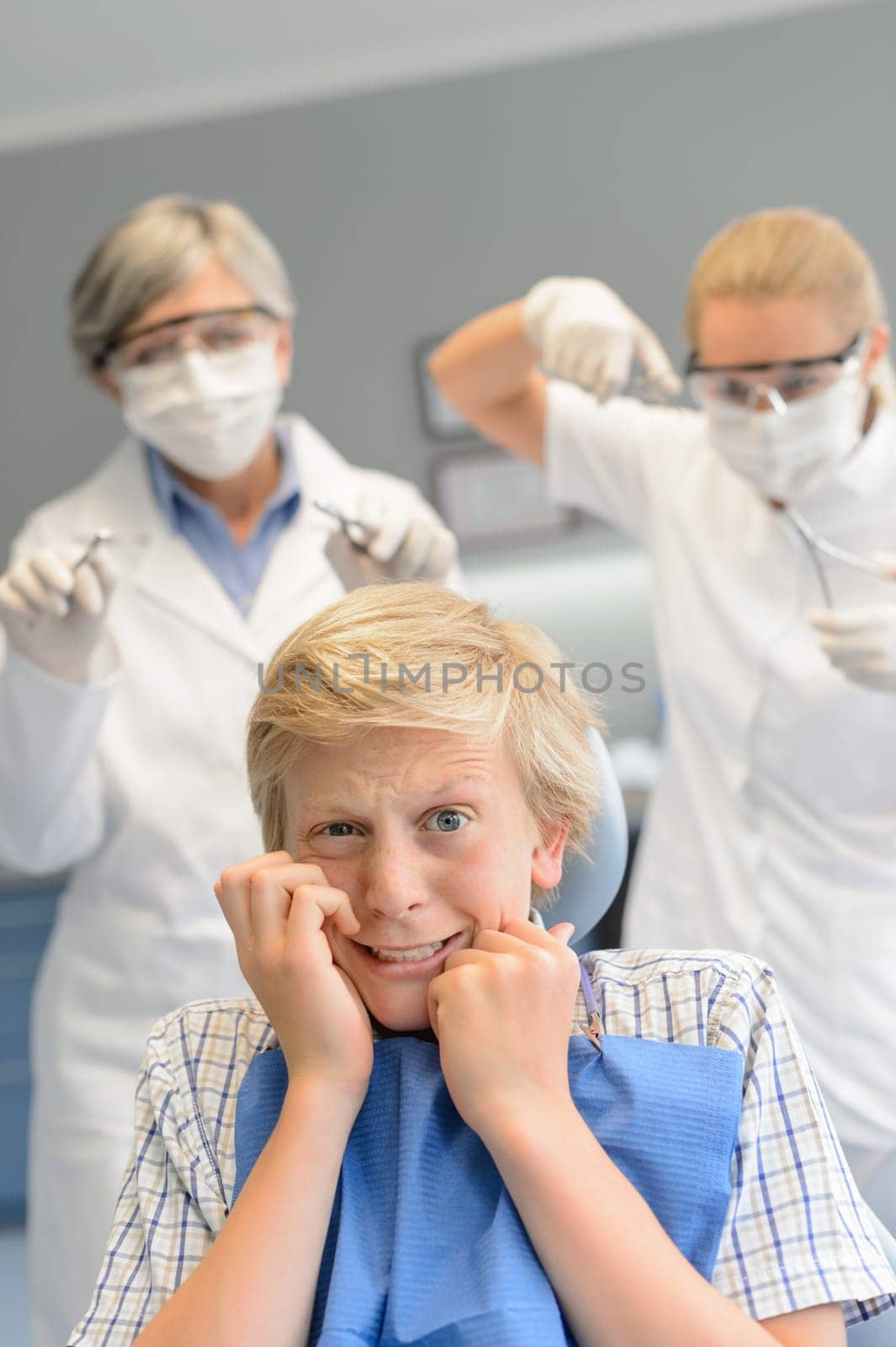Scared teenage boy at dental surgery dentist woman with assistant
