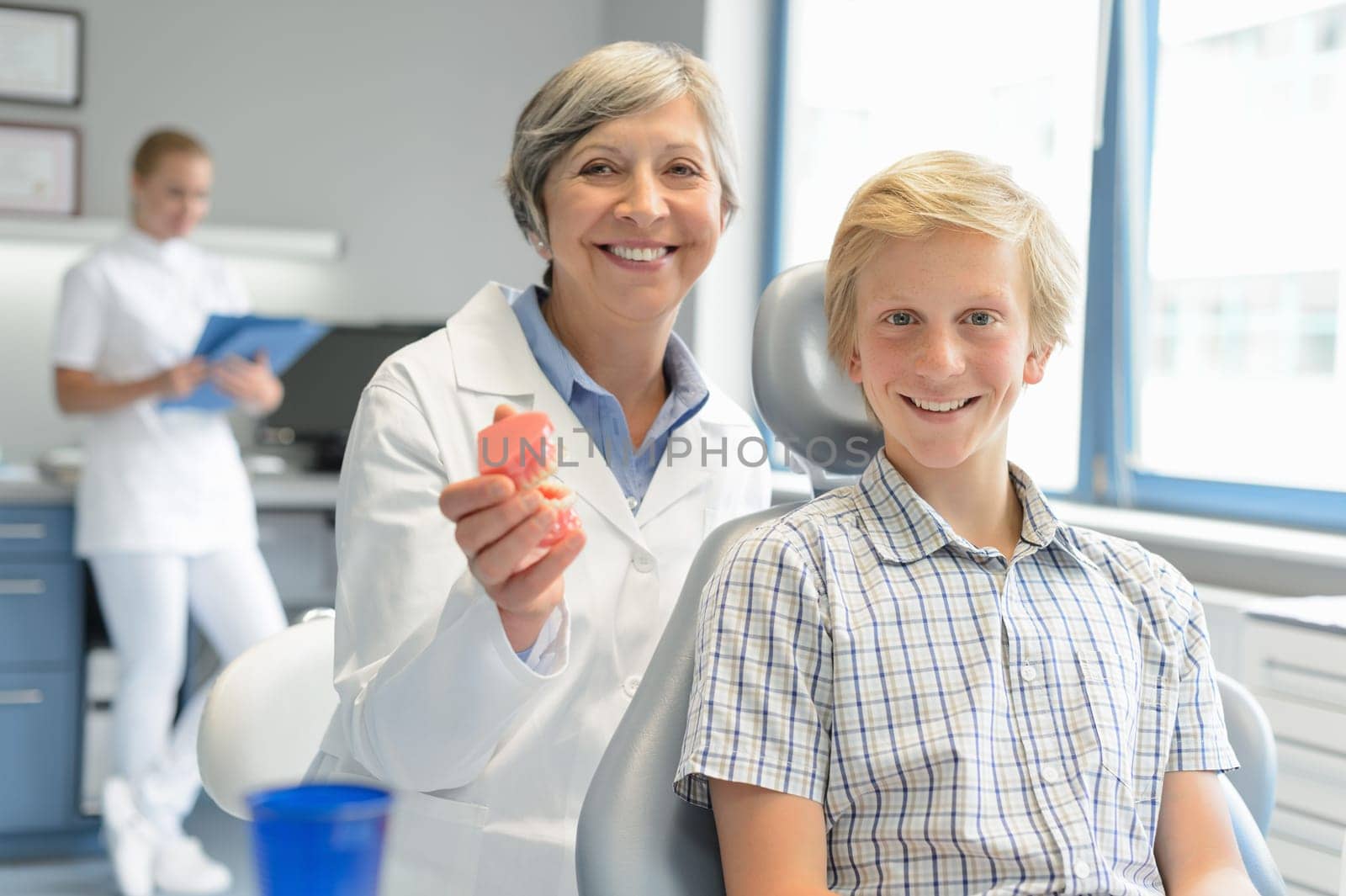 Teenager boy patient dentist hold teeth dentures dental assistant office