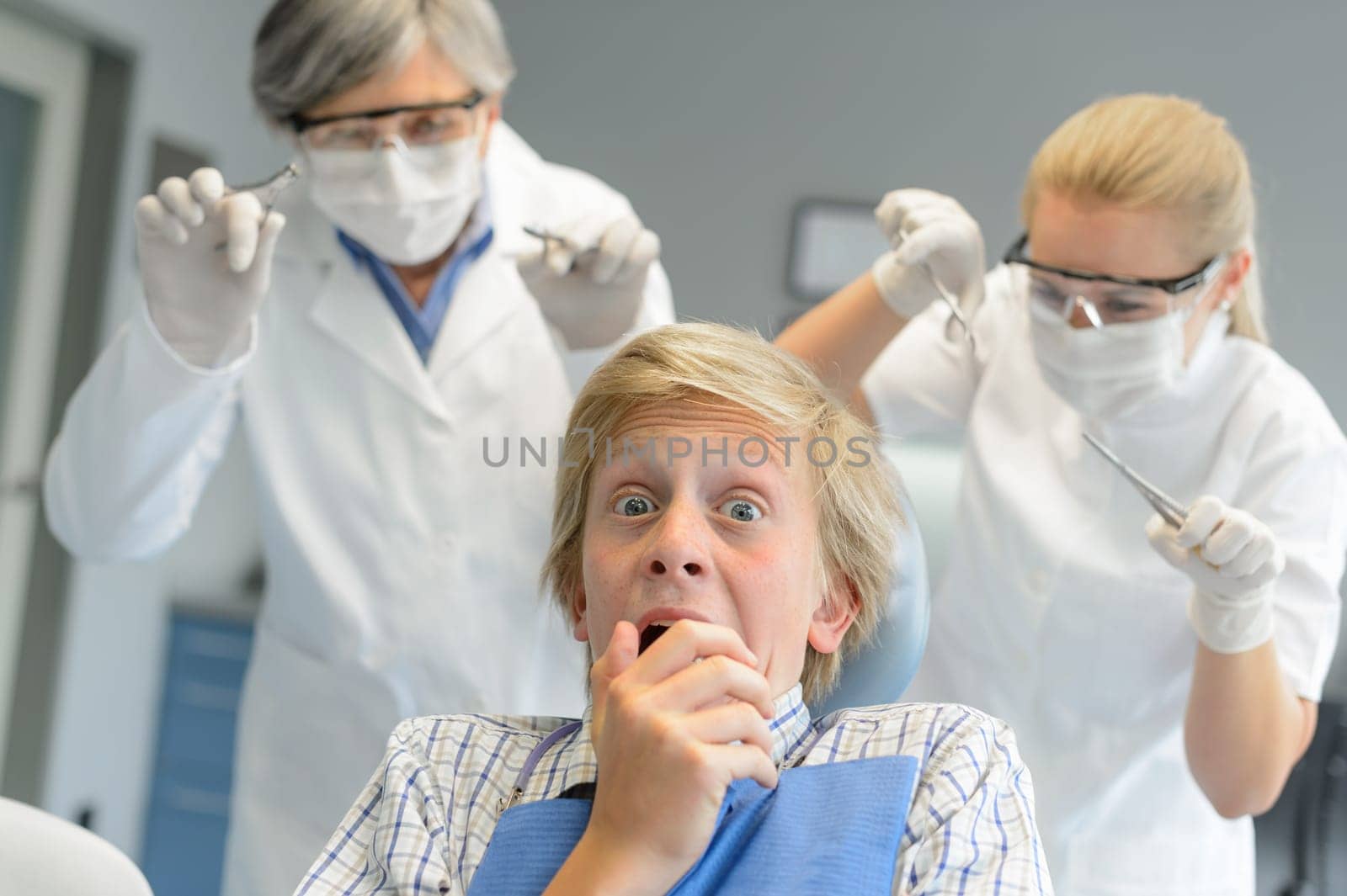 Scared teenage patient boy at dental clinic frightening dentist assistant