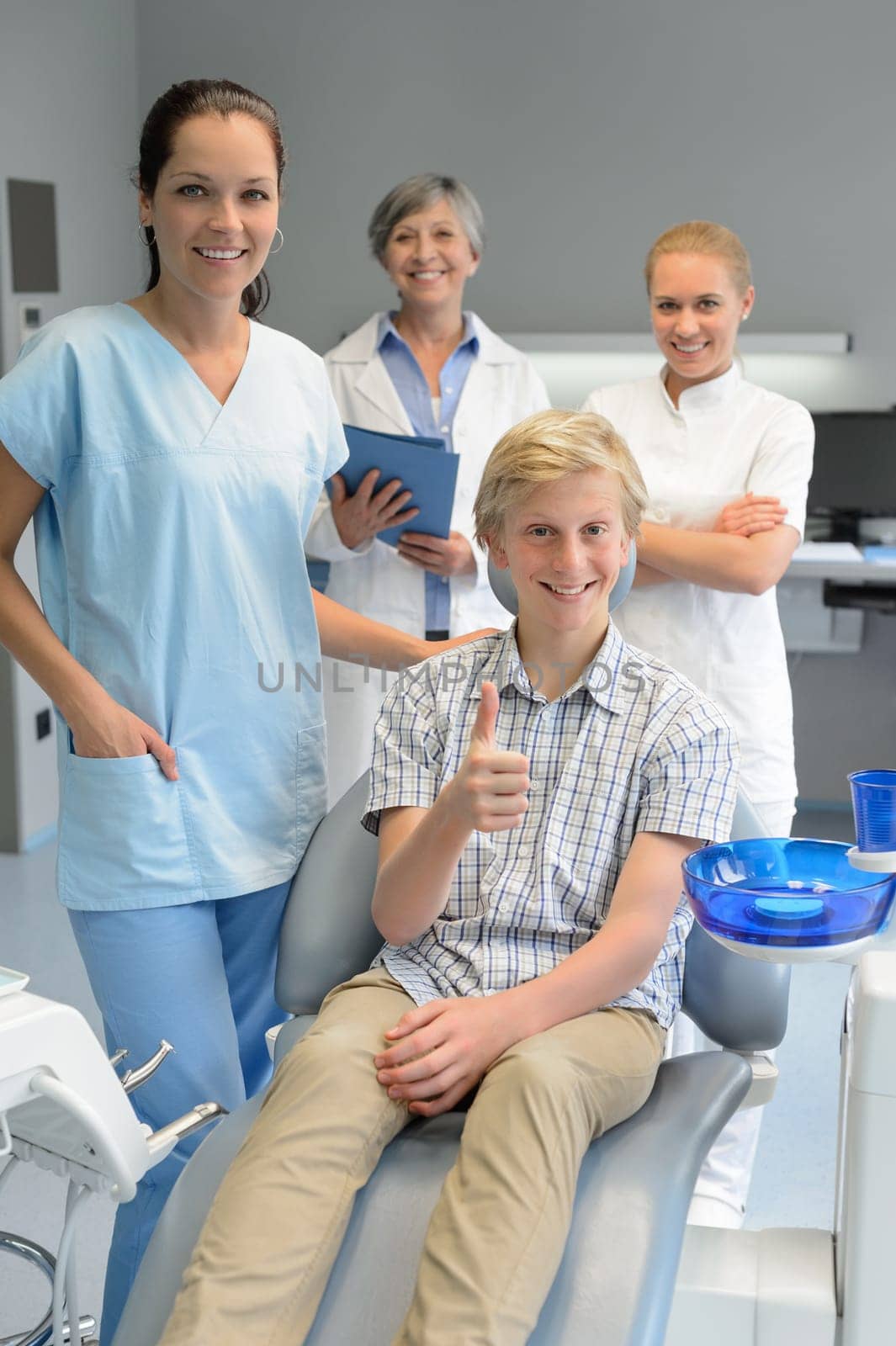 Professional dentist team with teenager boy patient thumbup dental surgery