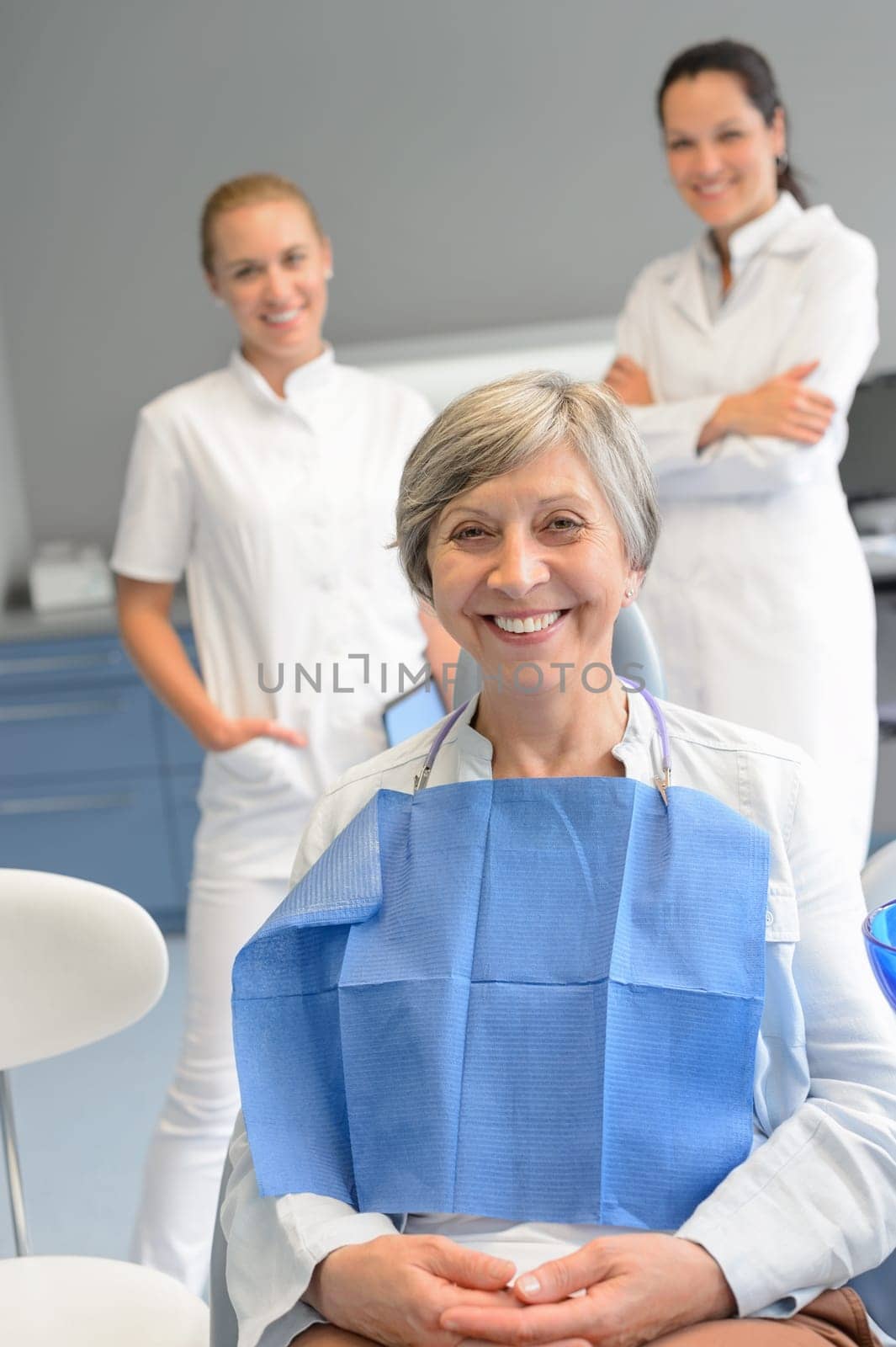 Senior woman patient with professional dentist team at dental surgery