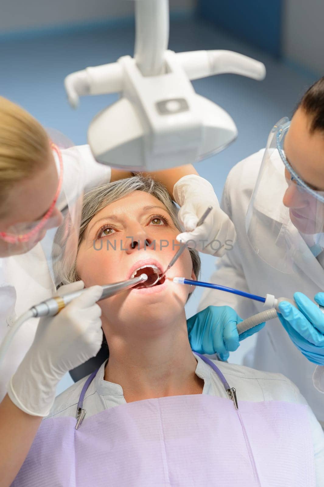 Elderly woman patient open mouth dental checkup professional dentist team