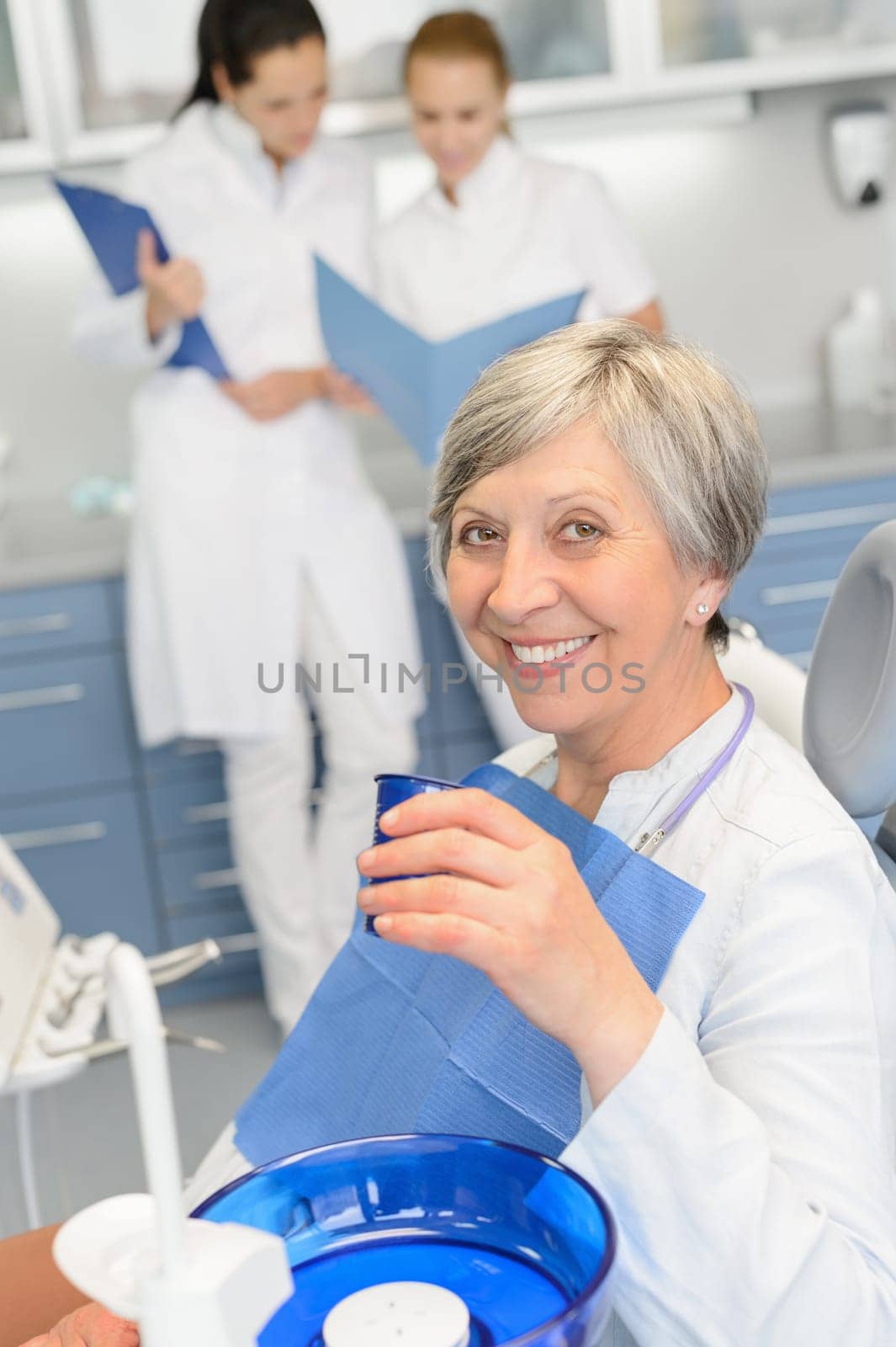 Elderly woman patient dentist team sitting chair at dental surgery