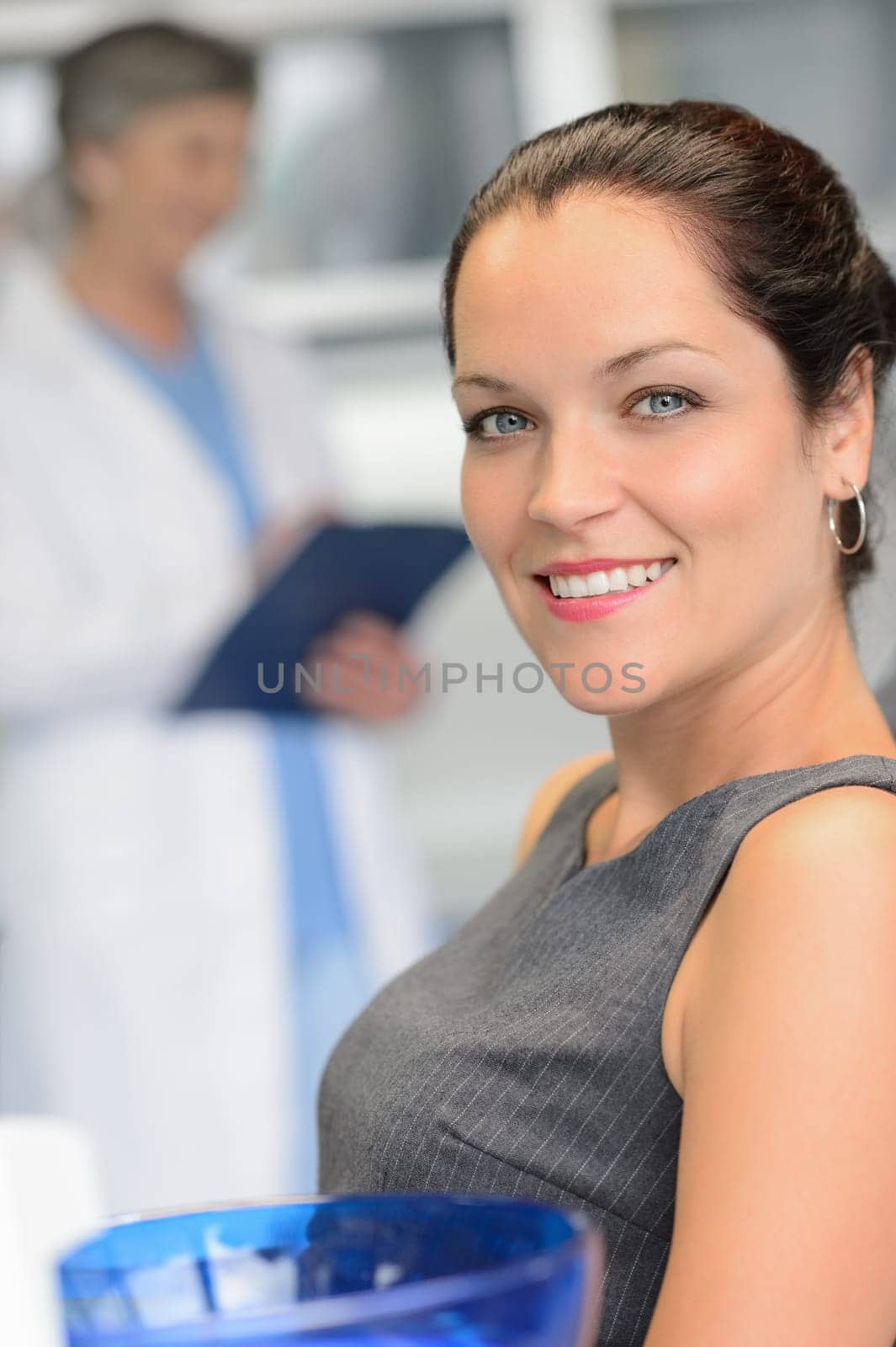 Elegant woman patient at dental surgery smiling dentist in background