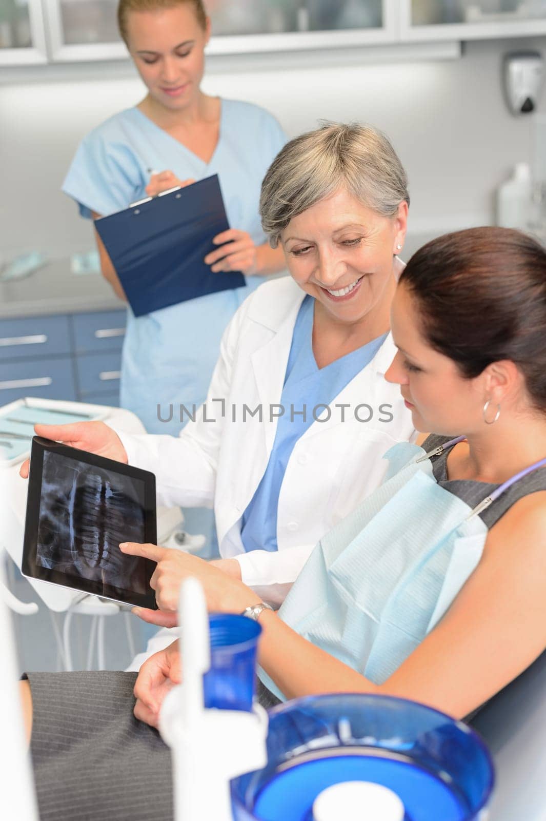 Woman patient at dental surgery dentist show teeth xray tablet