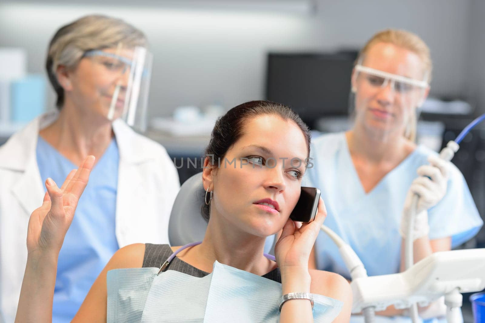 Impolite businesswoman on phone in dental office letting dentist wait