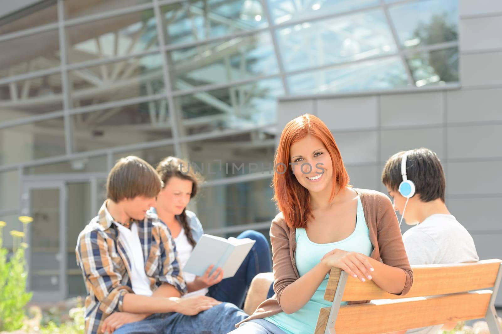 Smiling student girl with friends sitting bench outside college summer