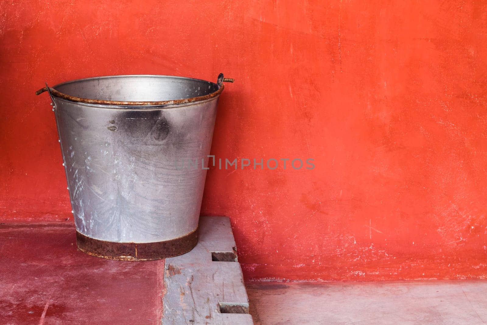 Small aluminum tank on step against red grunge wall