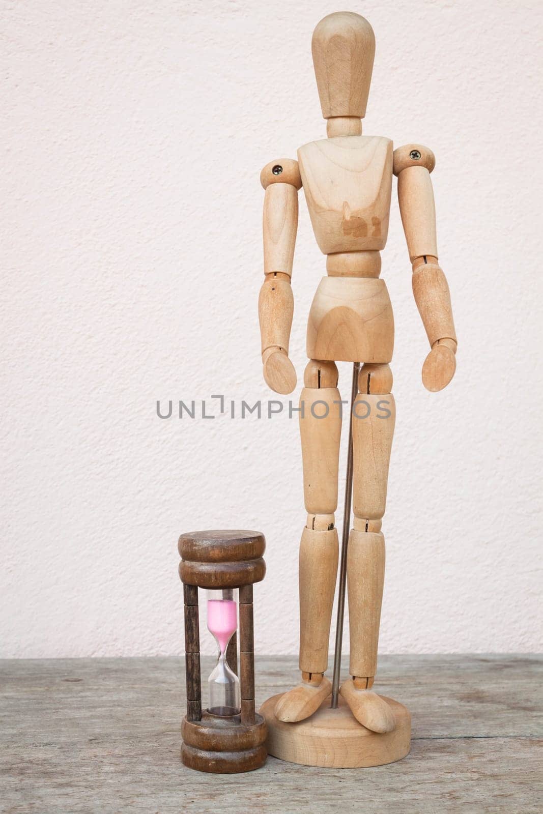 Wood mannequin and hourglass to represent spending time