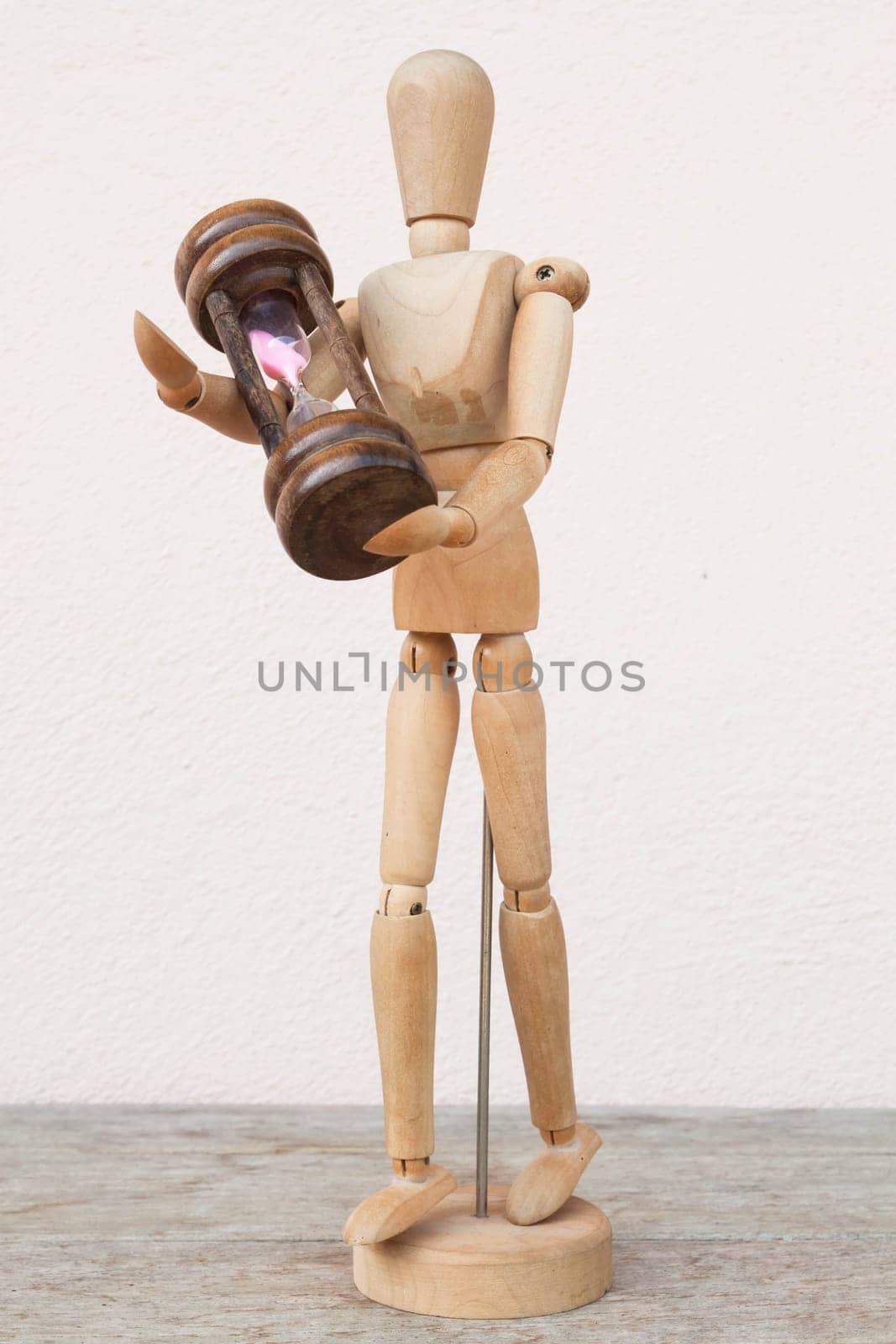 Wood mannequin and hourglass to represent time caring