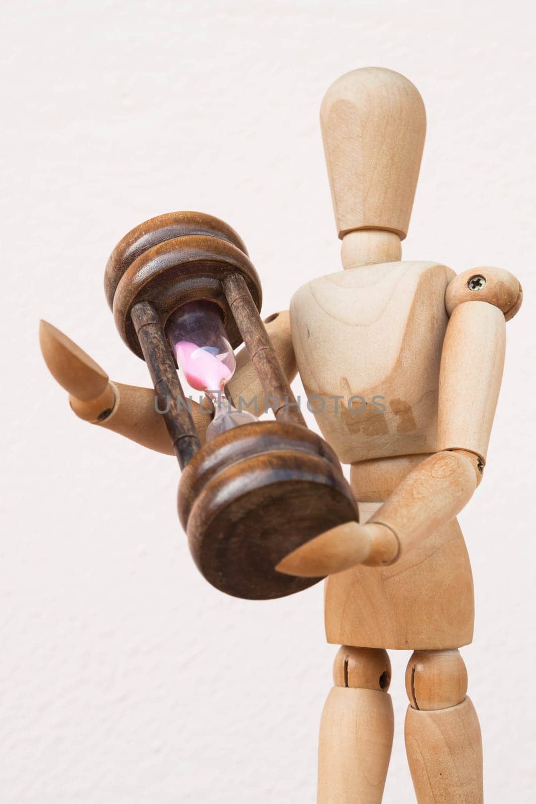Wood mannequin and hourglass to represent time giving