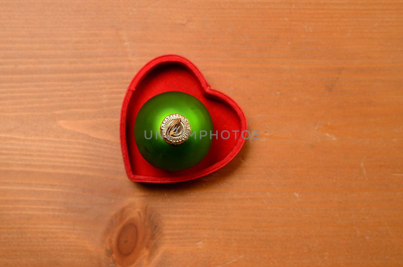 Green old Christmas bauble in a red heart shaped box