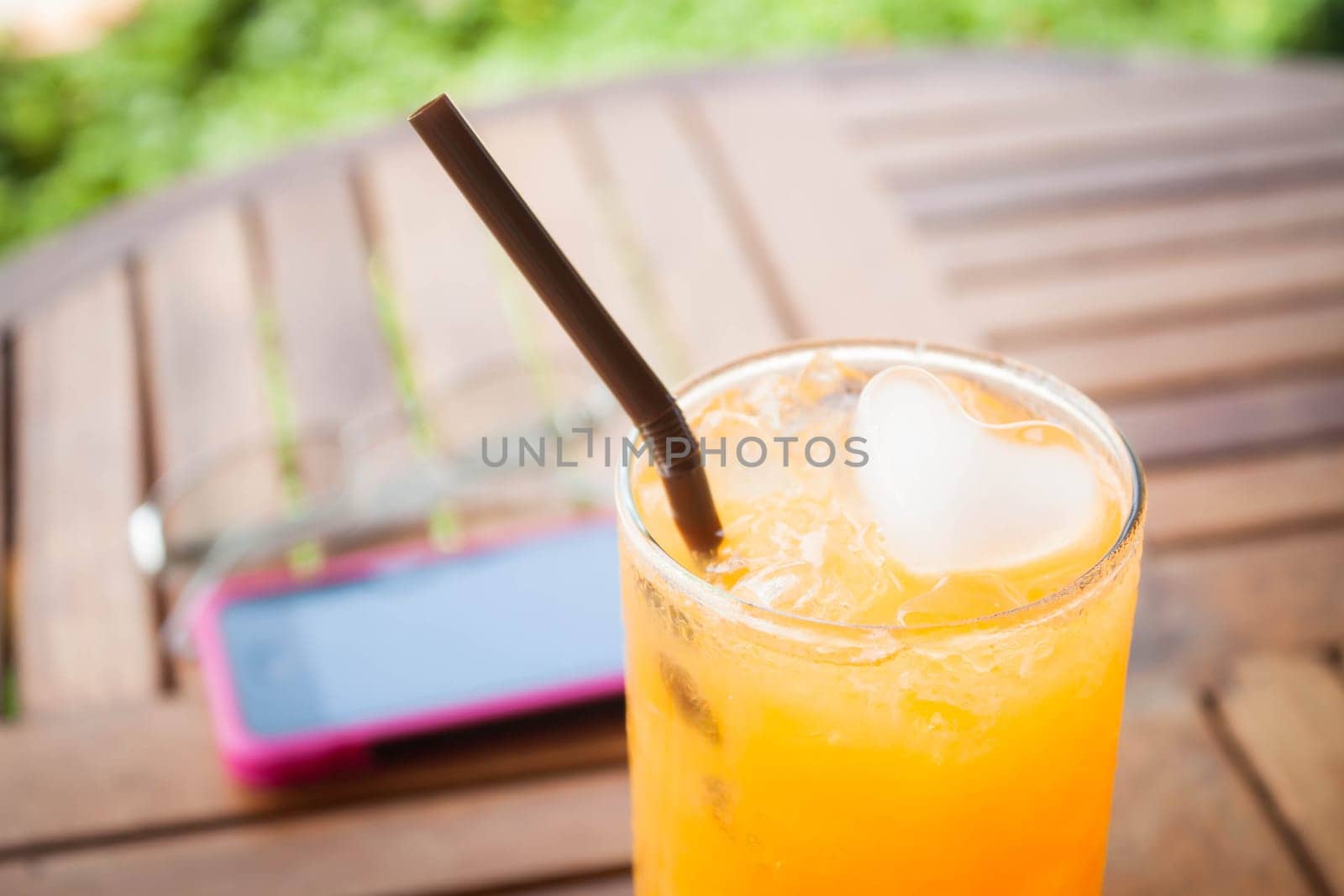Heart cube ice in fresh orange juice with straw