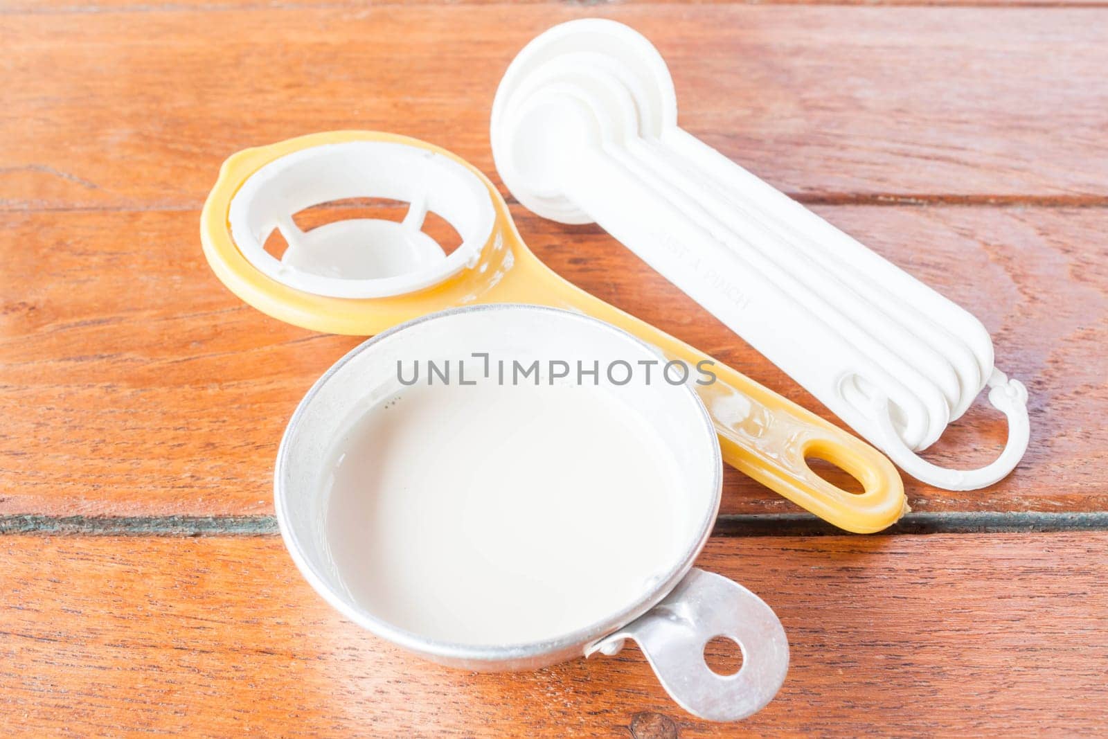 Beginning step of bakery preparation with milk, spoon and yolk separator