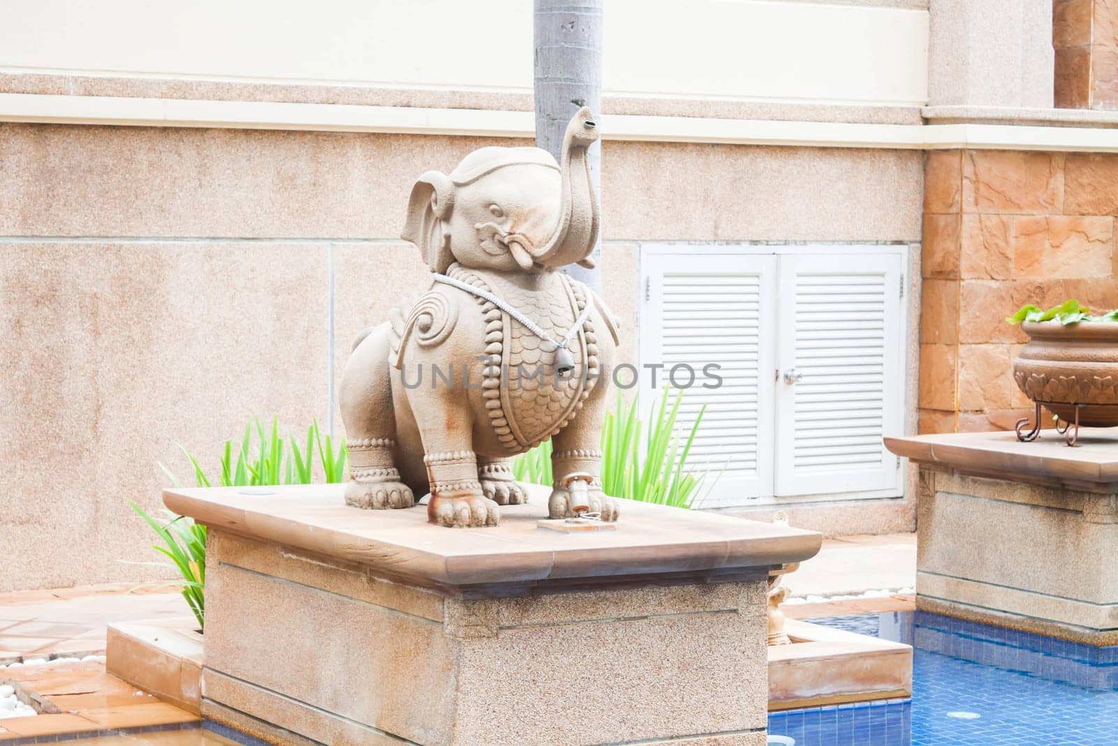 Elephant statue decorated beside tropical swimming pool