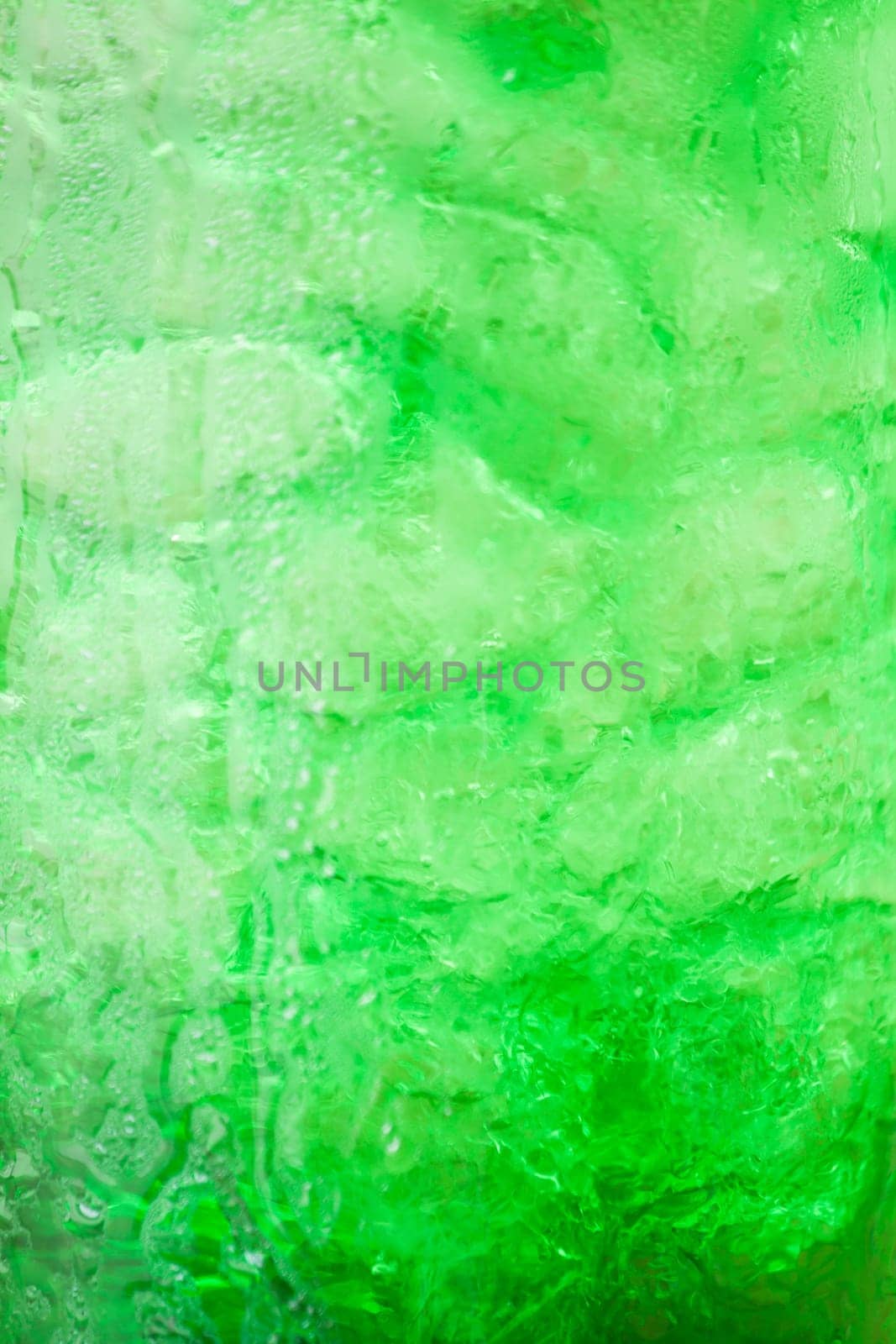 Green fizzy drink with ice cubes background