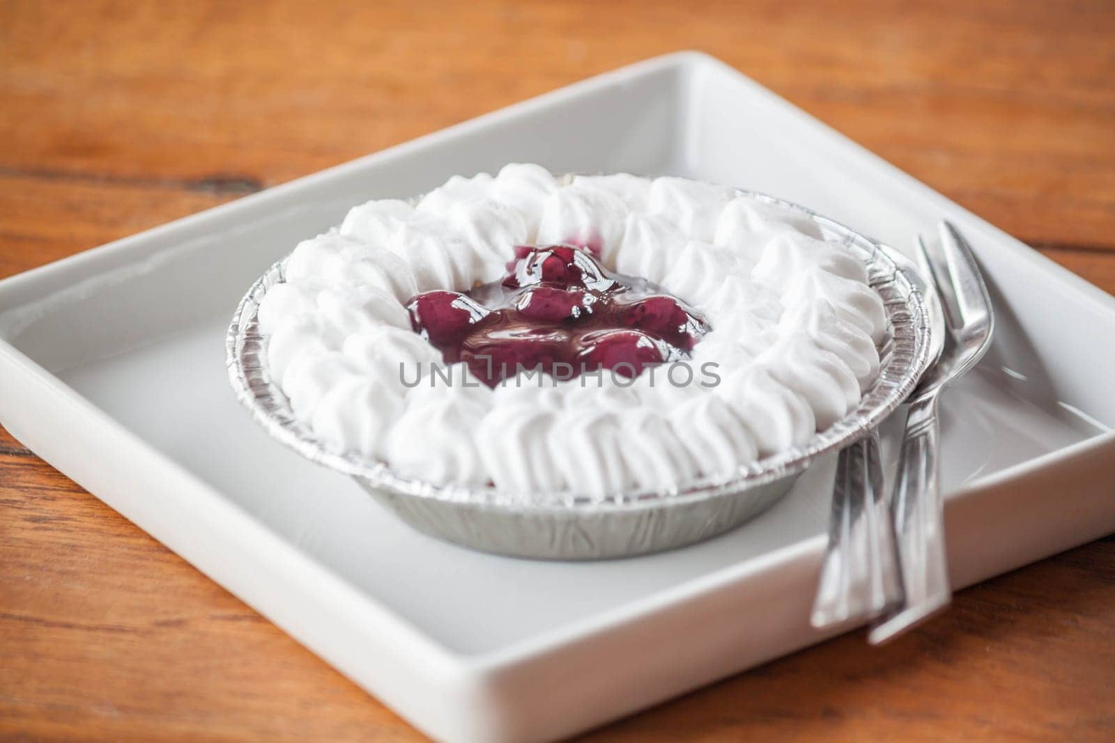 Blueberries cheese cupcake on white plate with spoon and fork