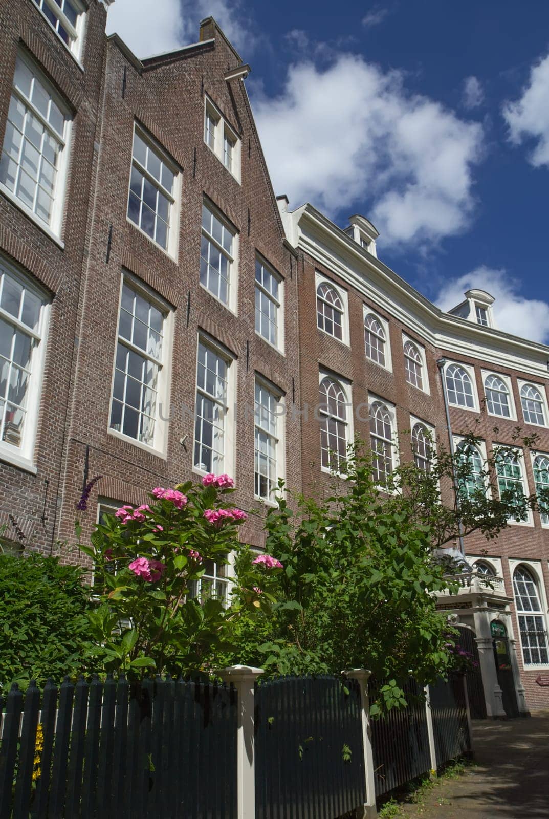 Typical Dutch houses in Amsterdam. Blue sky with clouds in the background.