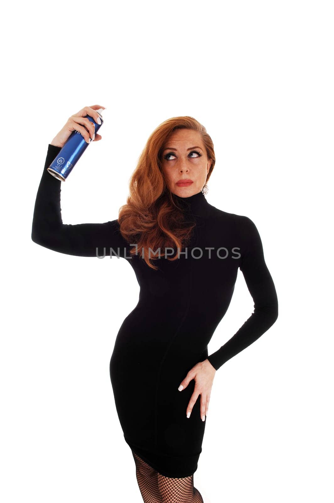 A classy woman in a black dress standing isolated for white background,.putting hair spray on her curly hair..