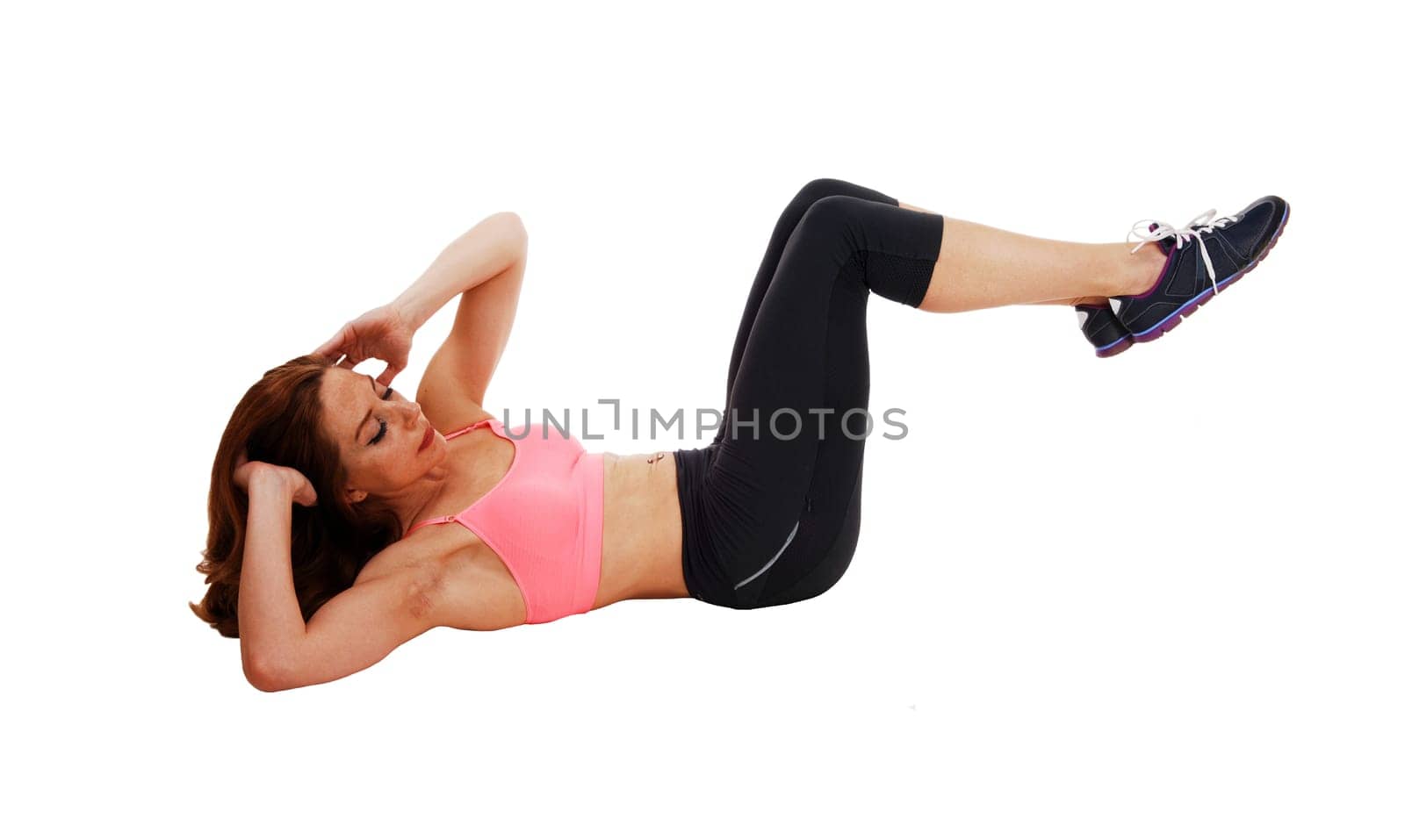 A slim pretty woman lying on the floor on her back doing stomach crunch,.isolated on white background..