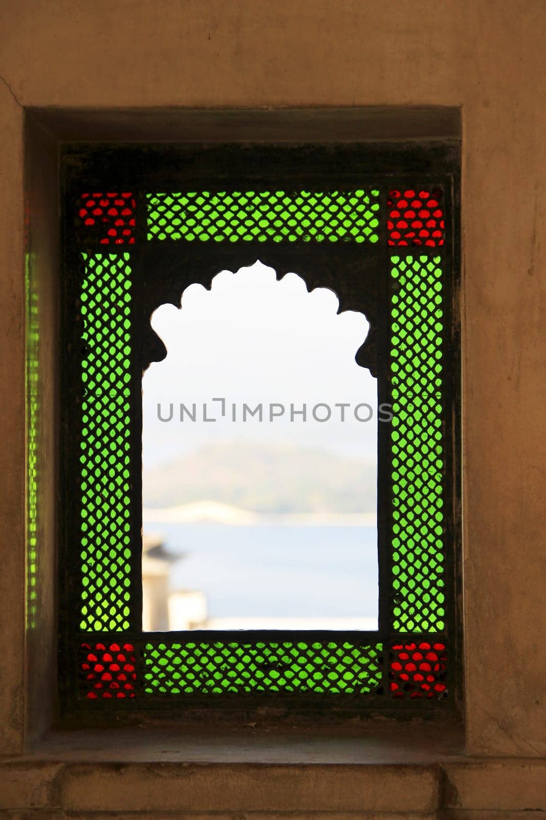 Arched balcony window framed with green and red color glass at City Palace, Udaipur, Rajasthan, India, Asia