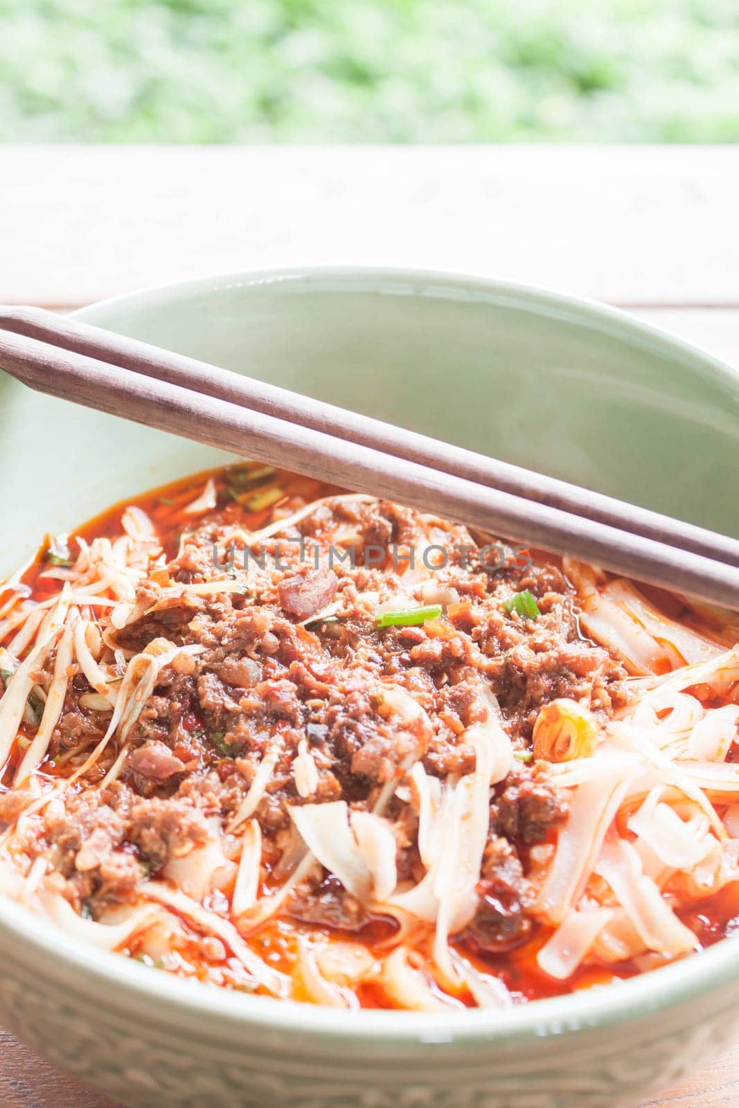 Spicy noodle in meat soup with chopsticks on table