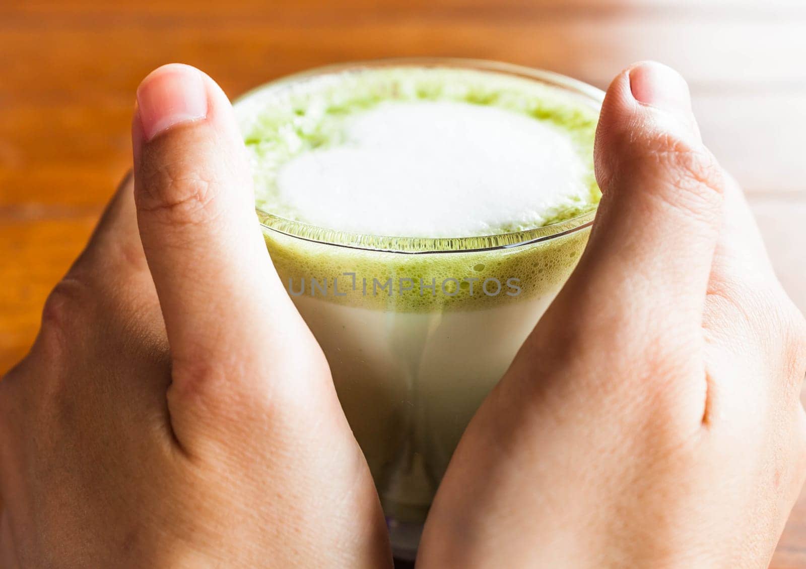 Hands hold hot drink of matcha green tea latte