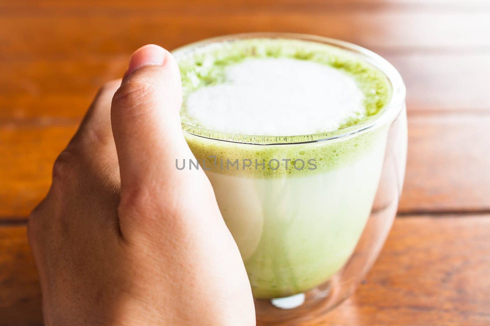 Hand on hot matcha green tea latte glass