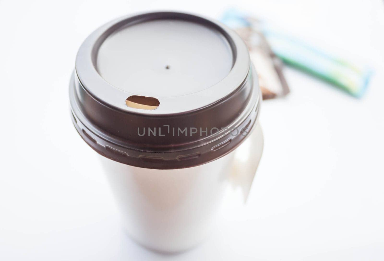Hot coffee in paper cup with sugar packs on white background