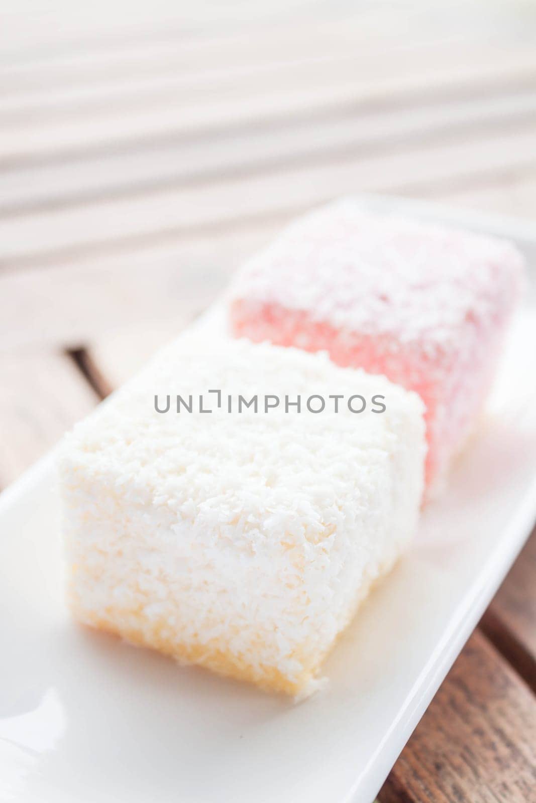 Pink and white lamington cakes on wood table, stock photo