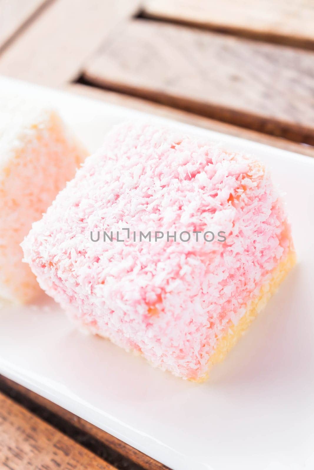 Pink lamington cakes up close on wood table, stock photo