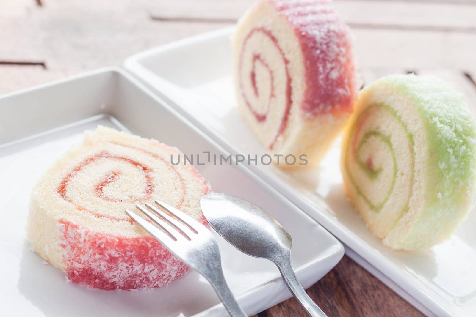 Slice of colorful jam roll on wood table, stock photo