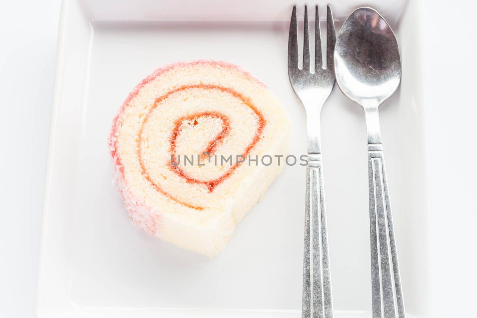 Strawberry jam lamington roll cake with spoon and fork, stock photo