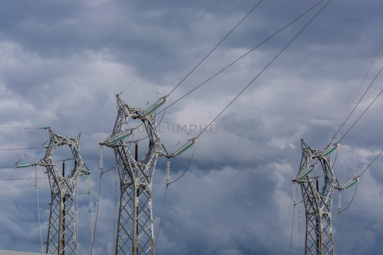 three electrical pylons on the background of a stormy sky