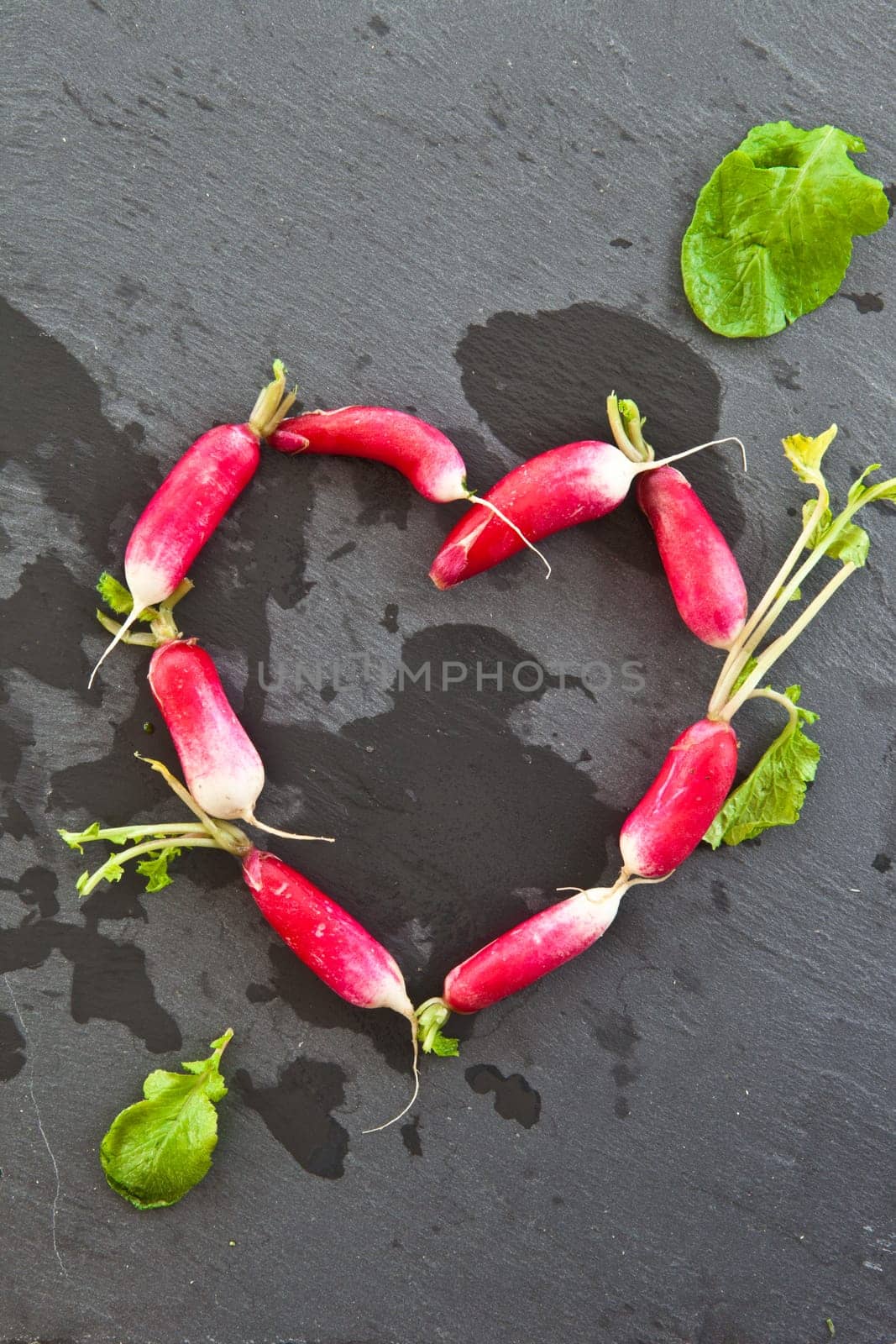 Fresh radishes in heart shape on slate plate