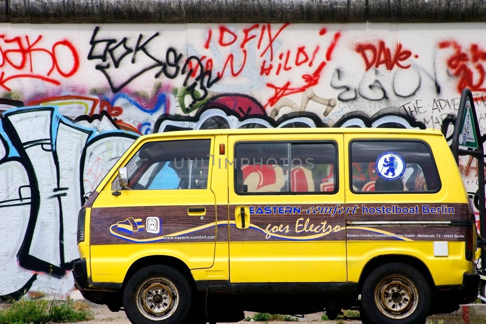 Berlin,Germany -June 16,2014: An old Volkswagen minibus of the Eastern Comfort Hostelboat stands in front of the East Side Gallery in Berlin on June 16,2014.
