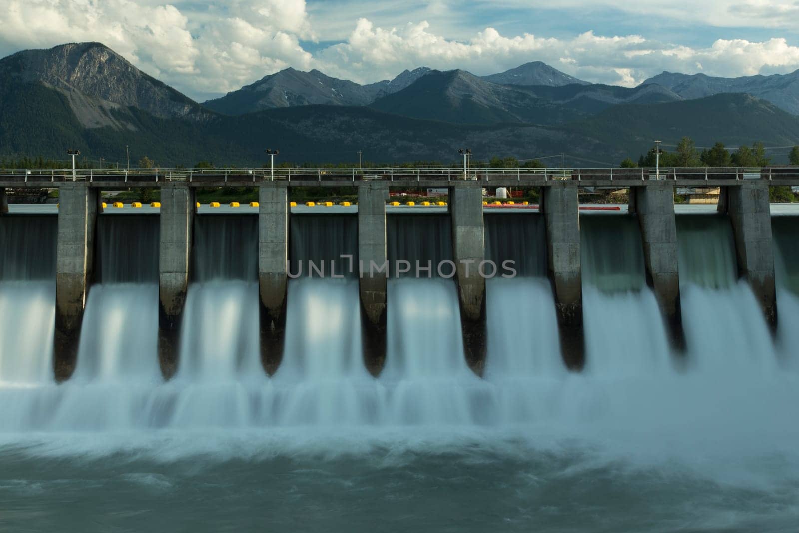 Wide time exposure of the spillway on the Kananaskis hydroelectric dam on the Bow River, with Canadian Rockies in the background in Alberta, Canada